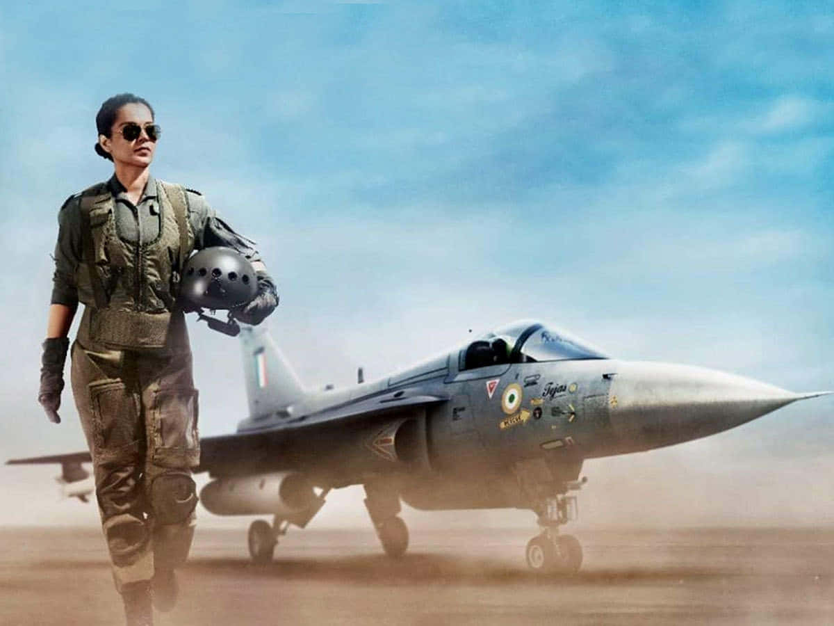 Pilot 桌布 壁紙 — 一名身穿制服的女戰鬥機飛行員自信地走在停泊在塵土飛揚的機場上的印度空軍噴射機旁，天空清澈湛藍。