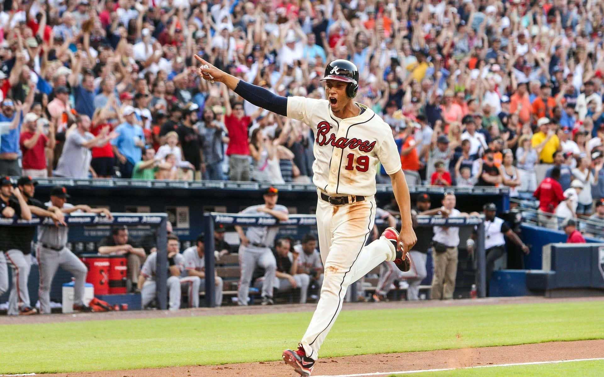 Atlanta Braves Desktop 桌布 壁紙 — 一名身穿勇士隊球衣的棒球選手高舉雙臂慶祝全壘打，球場內球迷歡呼。