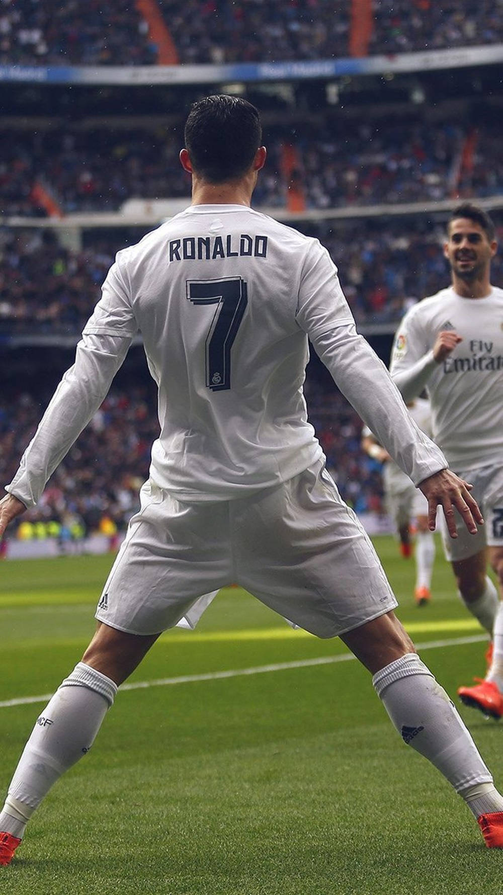克里斯蒂亞諾·羅納度 桌布 壁紙 — 一名身穿印有「RONALDO」和7號白色球衣的足球運動員在體育場燈光下於充滿活力的綠色球場上慶祝。