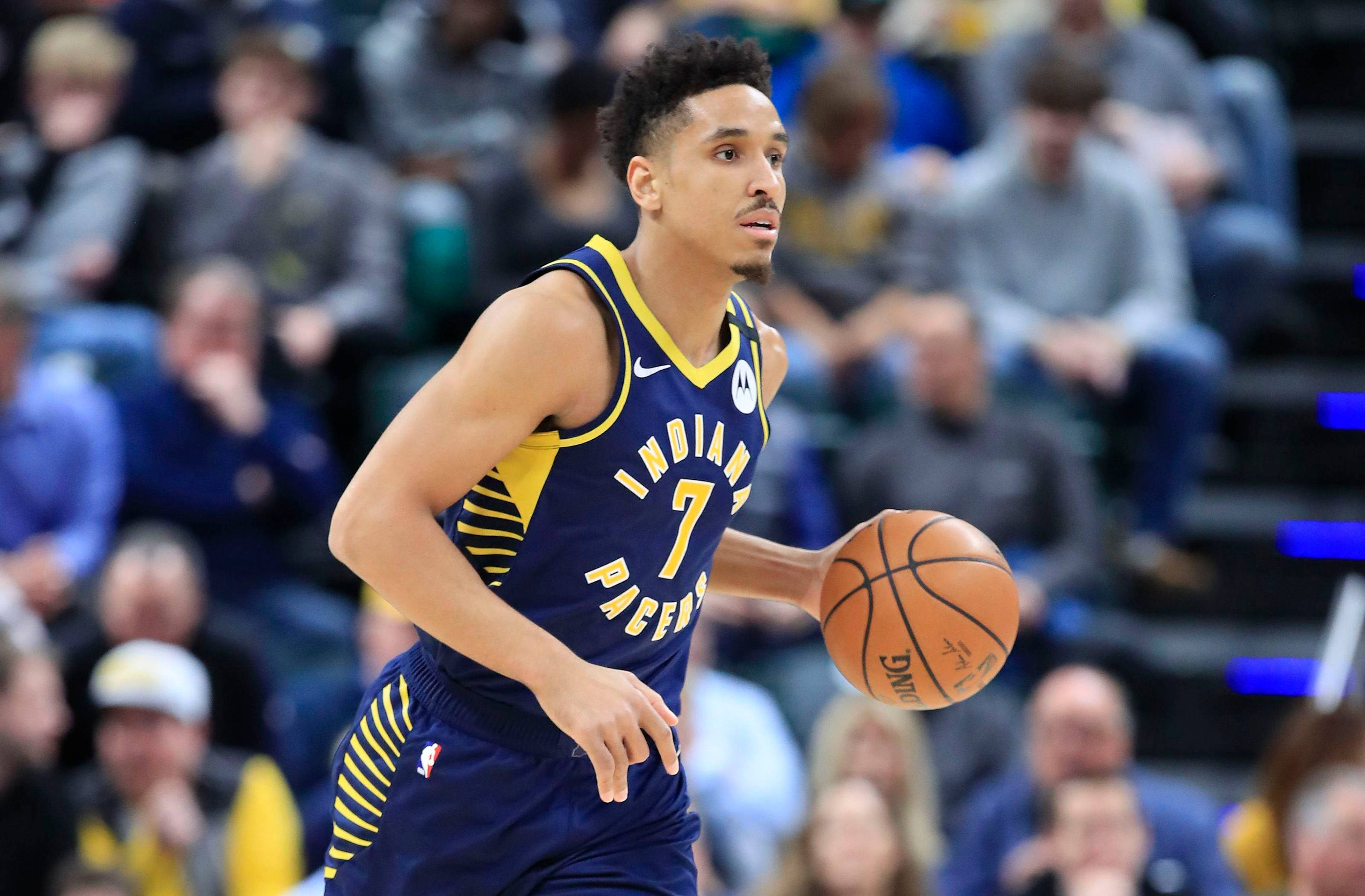 malcolm brogdon 桌布 壁紙 — 一名身穿印第安納溜馬球衣的籃球運動員在比賽中運球，背景有模糊的觀眾。