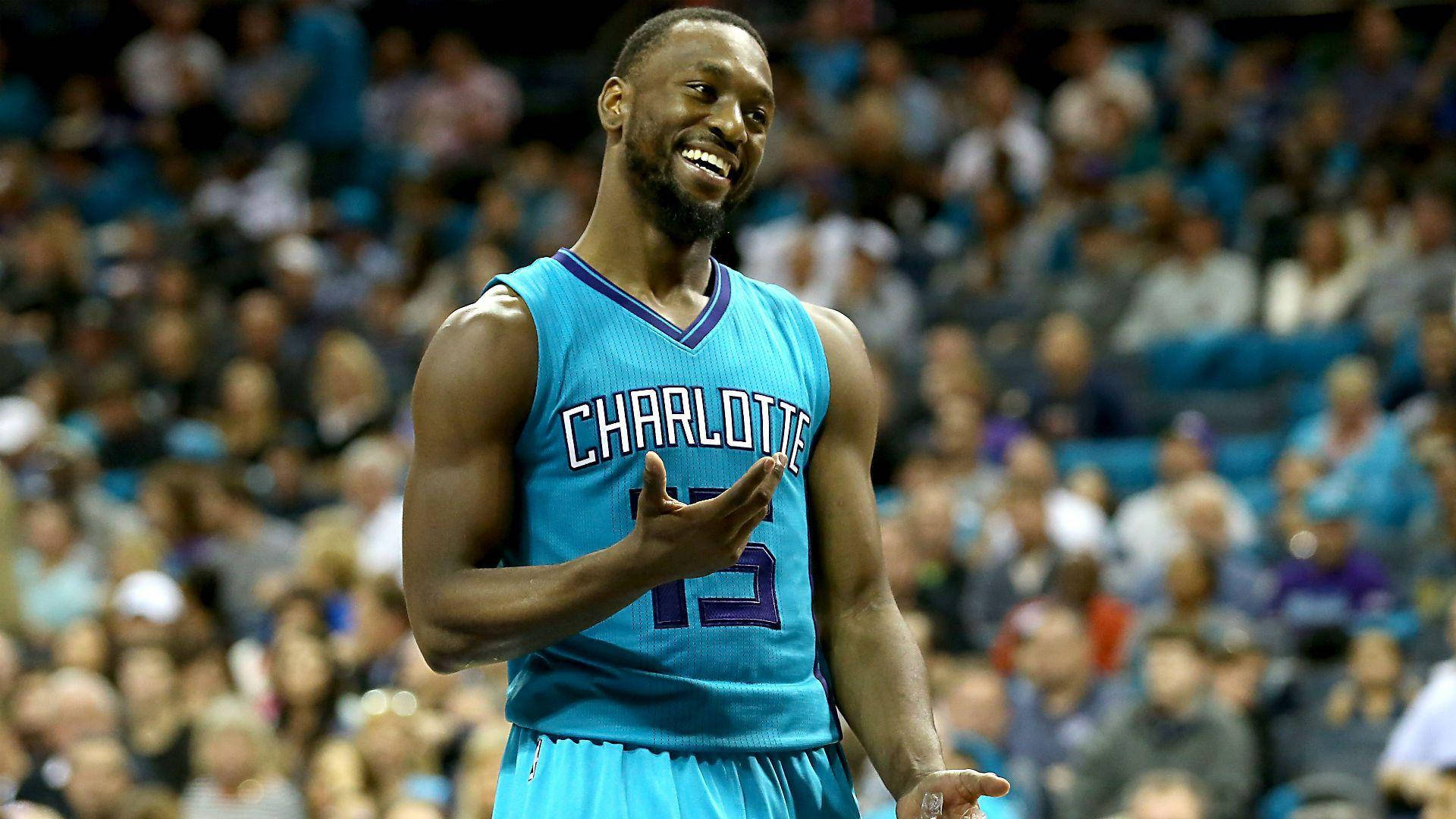 Kemba Walker 桌布 壁紙 — 一名身穿夏洛特球衣的籃球運動員在比賽中大笑並向人群做手勢。