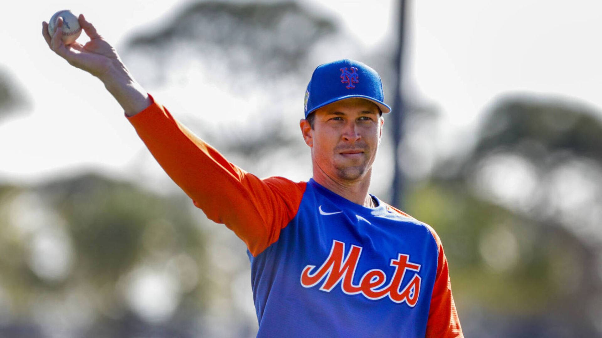 Degrom 桌布 壁紙 — 一名身穿大都會隊球衣的棒球選手，在模糊的戶外背景下，以專注的強度準備投球。
