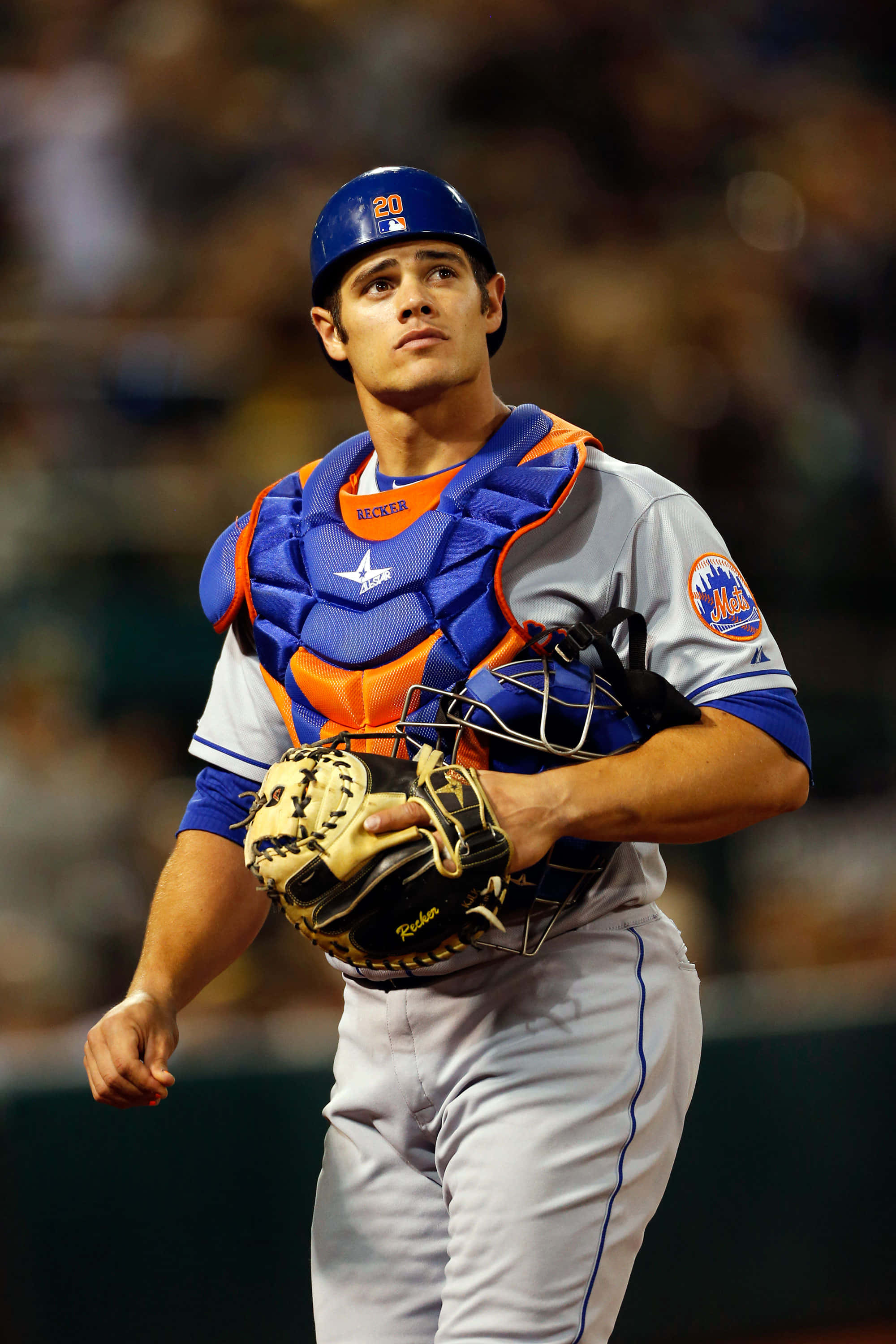 MLB Players 桌布 壁紙 — 一名身穿大都會隊裝備的棒球捕手在球場燈光下專注地站著，拿著手套和面罩。