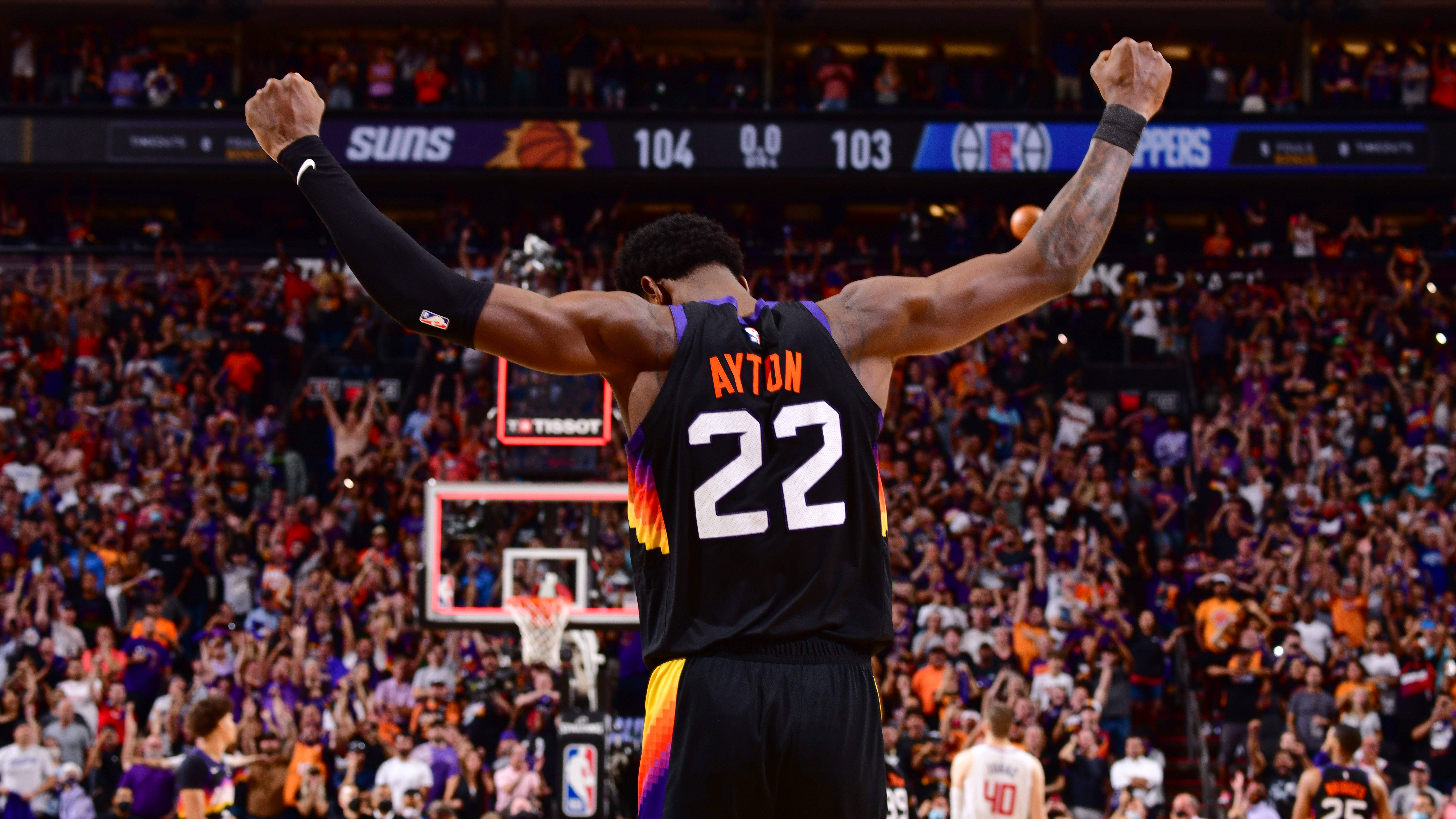 NBA 桌布 壁紙 — 一名身穿太陽隊球衣的籃球運動員在緊張比賽中高舉拳頭慶祝勝利，觀眾歡呼。