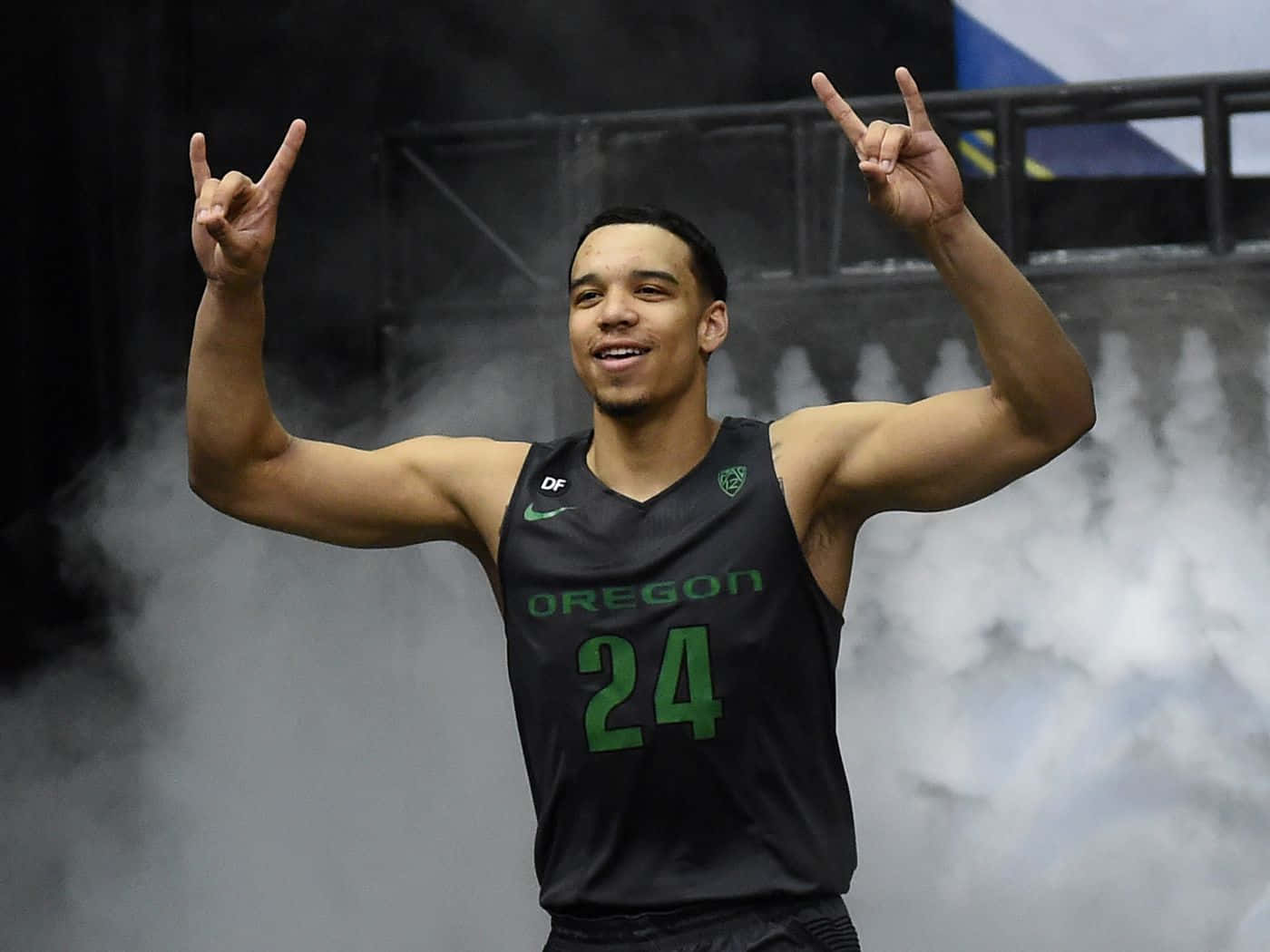 Dillon Brooks 桌布 壁紙 — 一名身穿奧勒岡球衣的籃球運動員在球場煙霧中做出搖滾手勢慶祝。