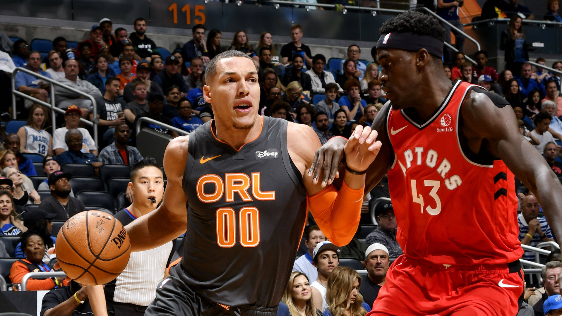 aaron gordon 桌布 壁紙 — 一名身穿奧蘭多球衣的籃球運動員在多倫多暴龍隊球員的緊密防守下運球，場館內人山人海。