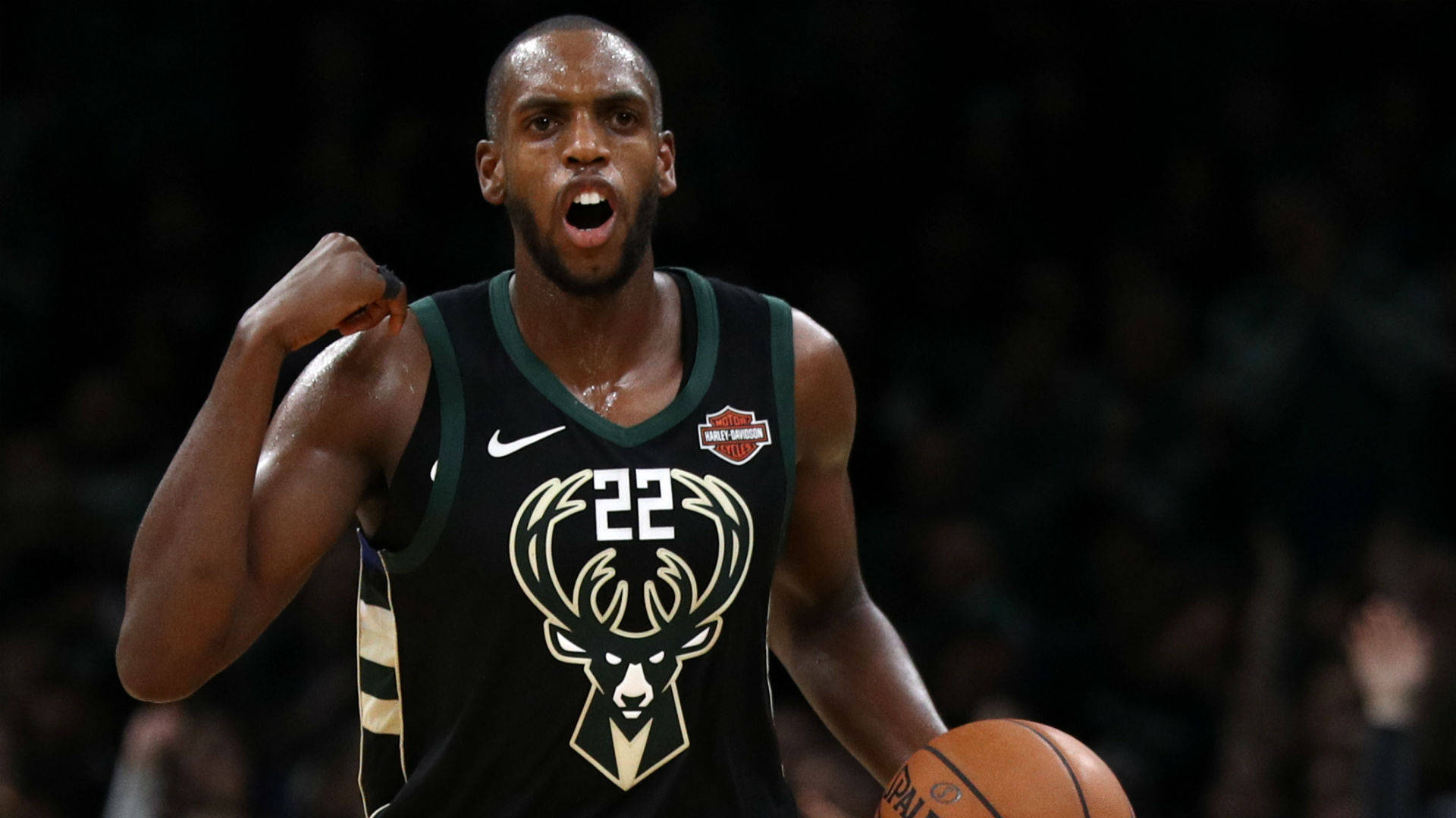 Khris Middleton 桌布 壁紙 — 一名身穿密爾瓦基公鹿隊球衣的籃球運動員，手持籃球並握緊拳頭，發出勝利的怒吼。