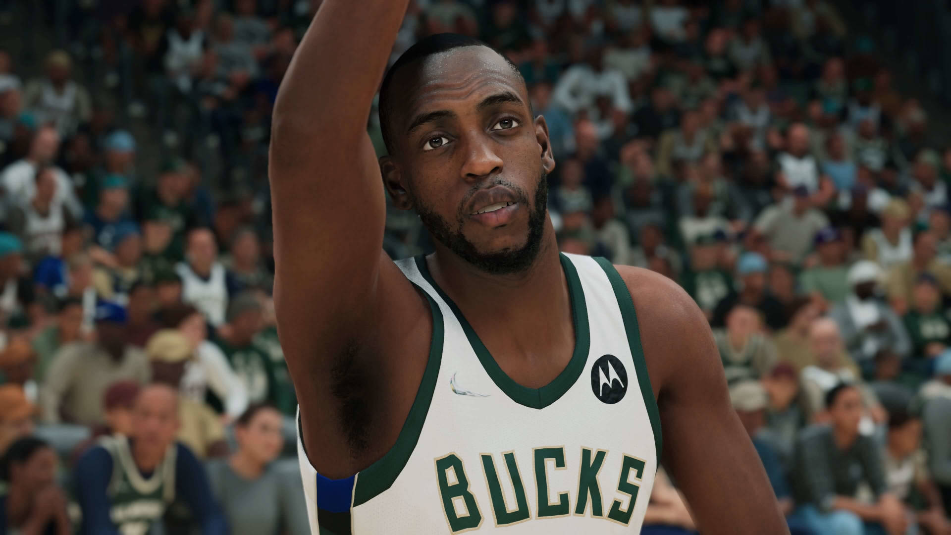 Khris Middleton 桌布 壁紙 — 一名身穿密爾瓦基公鹿隊球衣的籃球運動員在擠滿觀眾的場館中，對焦舉起手臂，背景人群模糊。