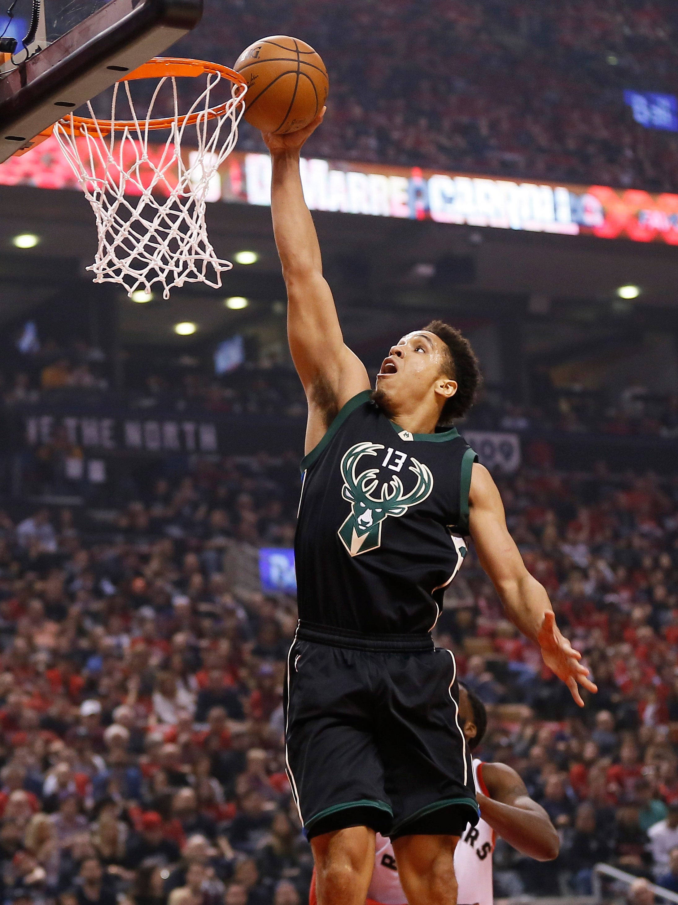 malcolm brogdon 桌布 壁紙 — 一名身穿密爾瓦基公鹿隊球衣的籃球運動員，在座無虛席的場館比賽中，專注地灌籃。