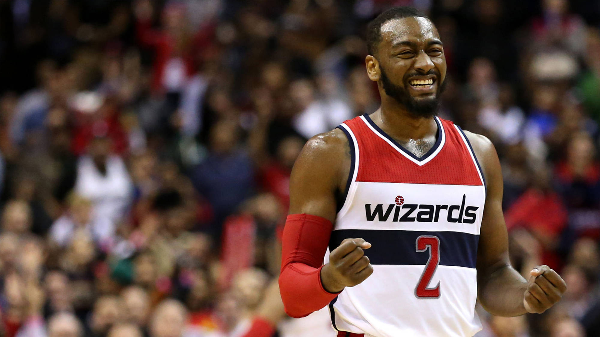 John Wall 桌布 壁紙 — 一名身穿巫師隊球衣的籃球運動員在比賽中咧嘴大笑、握緊拳頭慶祝。