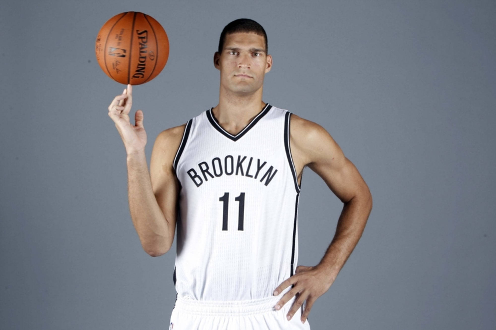 Brook 桌布 壁紙 — 一名身穿布魯克林球衣的籃球運動員在純灰色攝影棚背景前，用指尖平衡一個斯伯丁籃球。