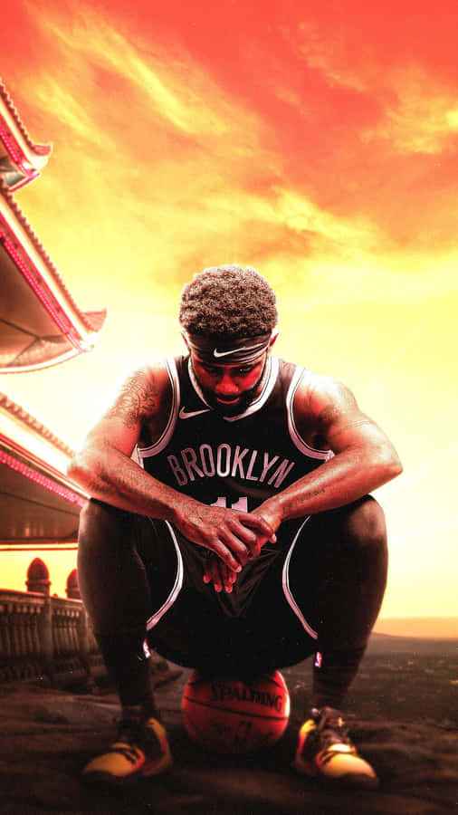 Kyrie Irving Cool 桌布 壁紙 — 一名身穿布魯克林球衣的籃球運動員，在熾熱的日落天空和傳統建築背景下，蹲下身子拿著球。