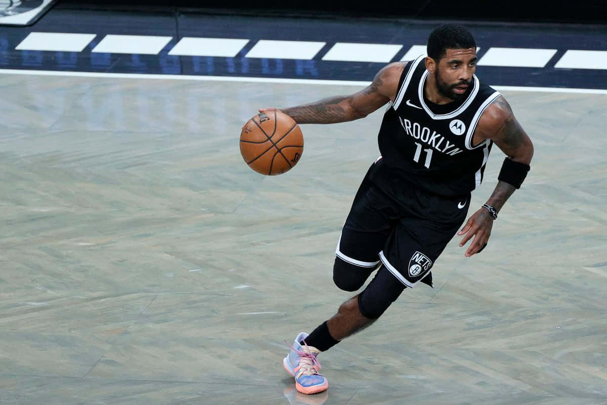 Kyrie Irving Nets 桌布 壁紙 — 一名身穿布魯克林籃網球衣的籃球運動員在拋光球場上專注地運球。