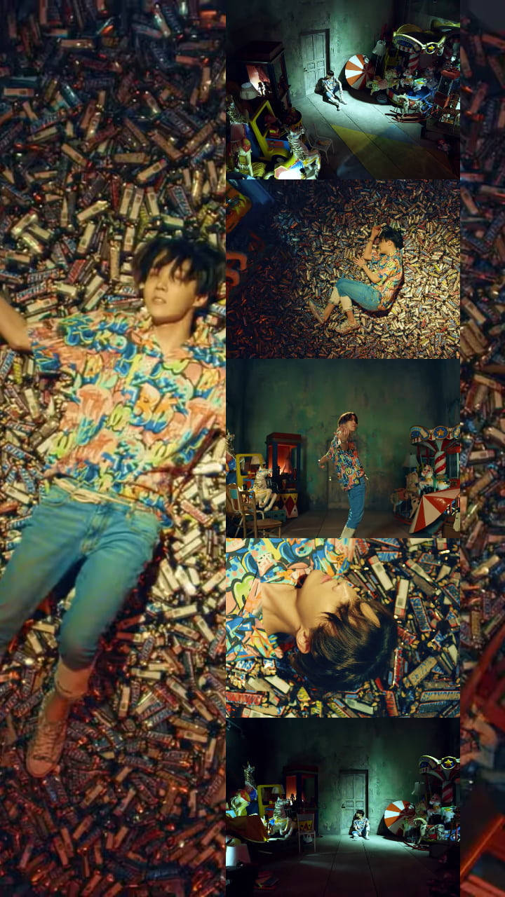 jhope 桌布 壁紙 — 一名身穿彩色襯衫的年輕男子躺在昏暗雜亂的房間裡，周圍散落著大量廢棄電池。