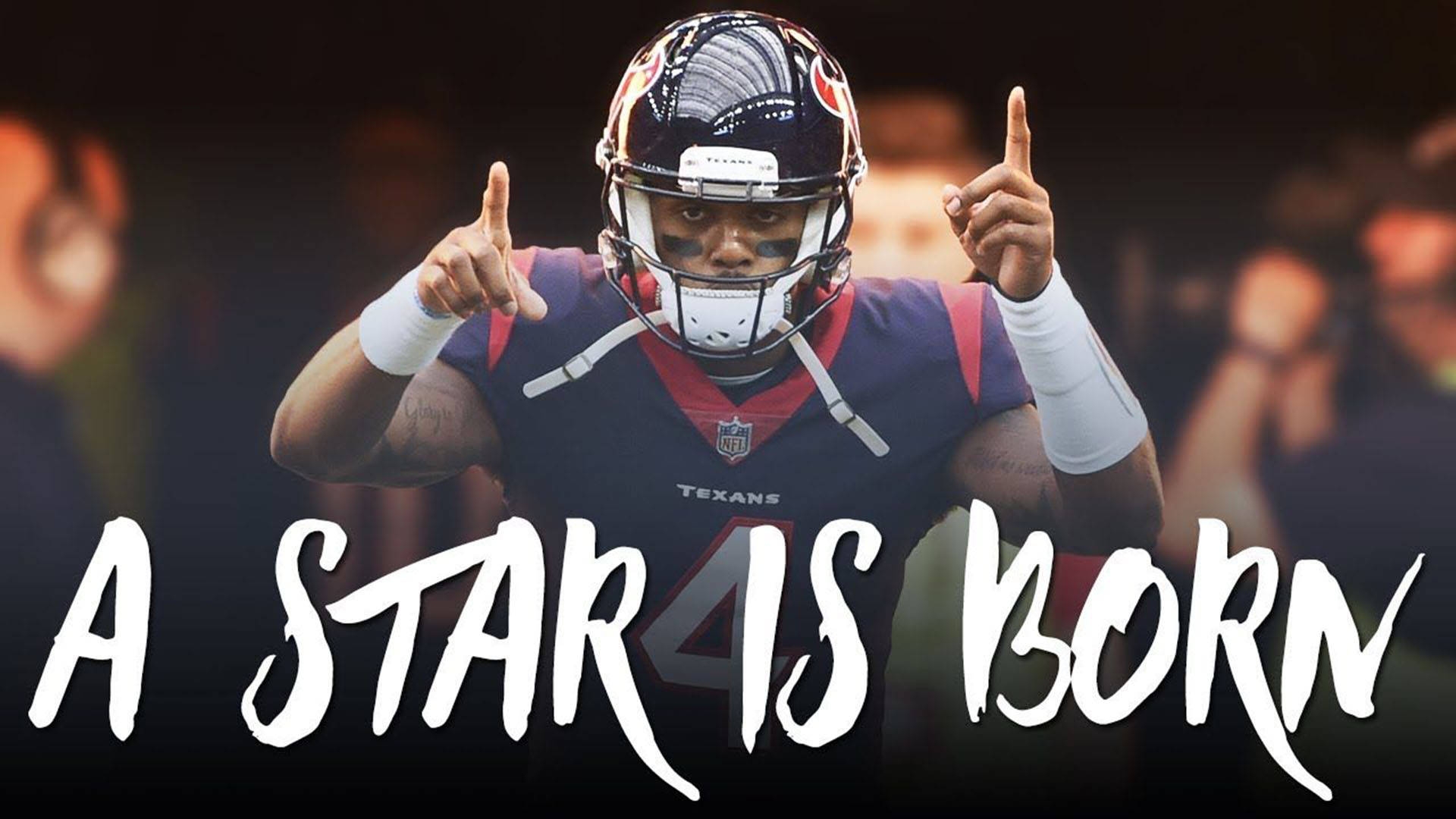 Deshaun Watson 桌布 壁紙 — 一名身穿德州人球衣的足球員在模糊的人群背景下雙手向上指，並有粗體文字寫著 'A STAR IS BORN'。