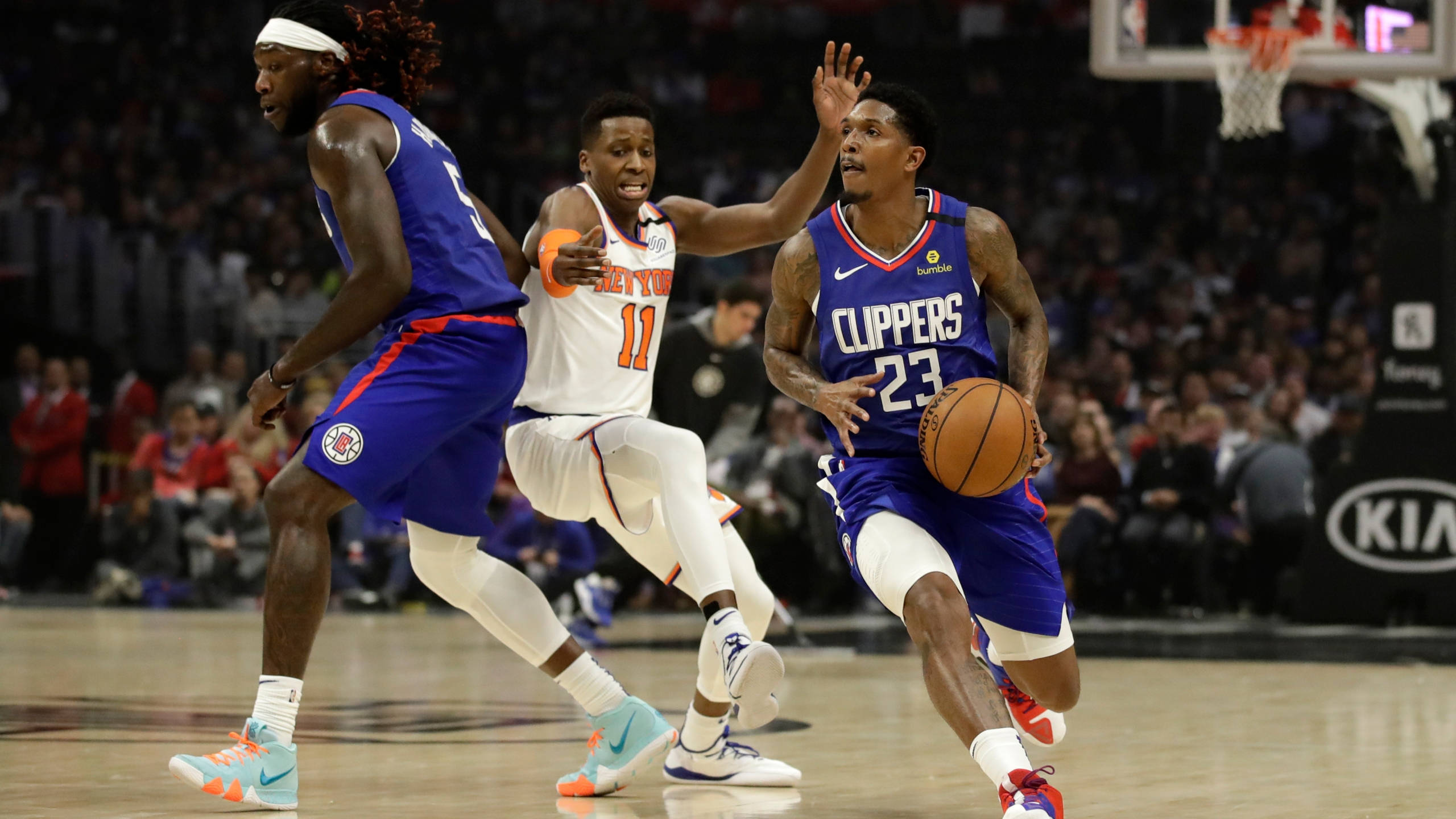 Lou Williams 桌布 壁紙 — 一名身穿快艇隊球衣的籃球運動員在激烈的比賽中運球，同時被兩名對手防守。