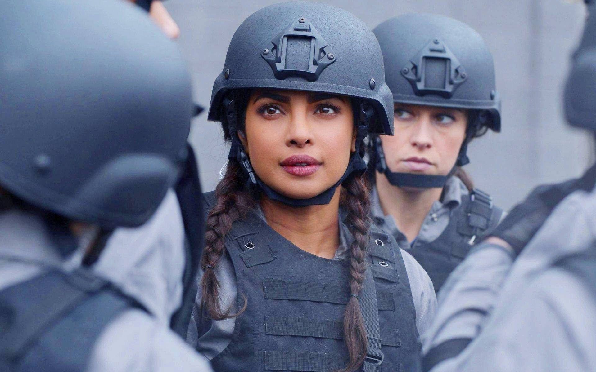 Fbi 桌布 壁紙 — 一名身穿戰術裝備、辮子頭髮的女性，在戴頭盔的戰友包圍下專注地凝視。