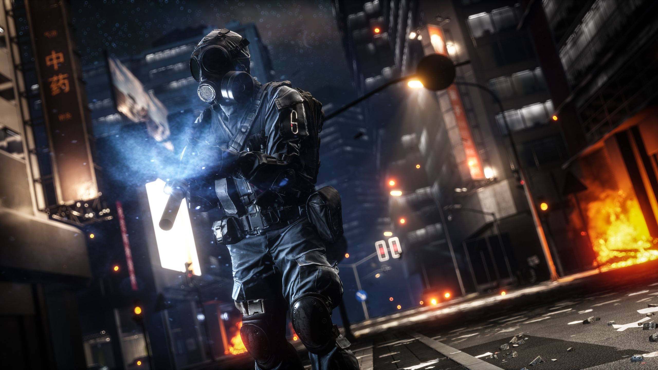 Battlefield 4 桌布 壁紙 — 一名身穿戰術裝備和防毒面具的士兵，夜晚站在霓虹燈照亮、燃燒的城市街道上。