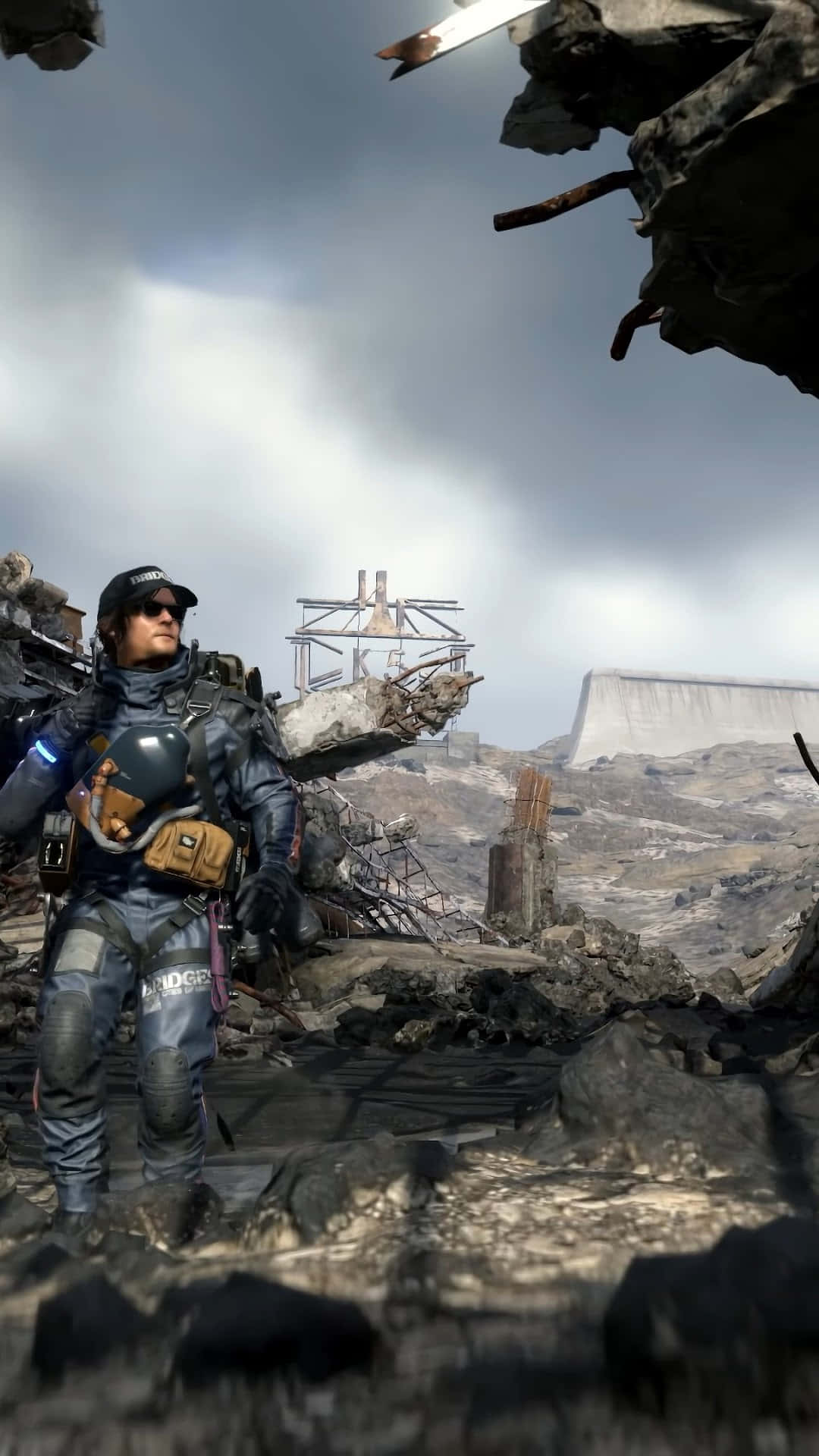 HD Death Stranding 桌布 壁紙 — 一名身穿戰術裝備的士兵站在陰天下的廢墟中，身處被毀的工業荒地。