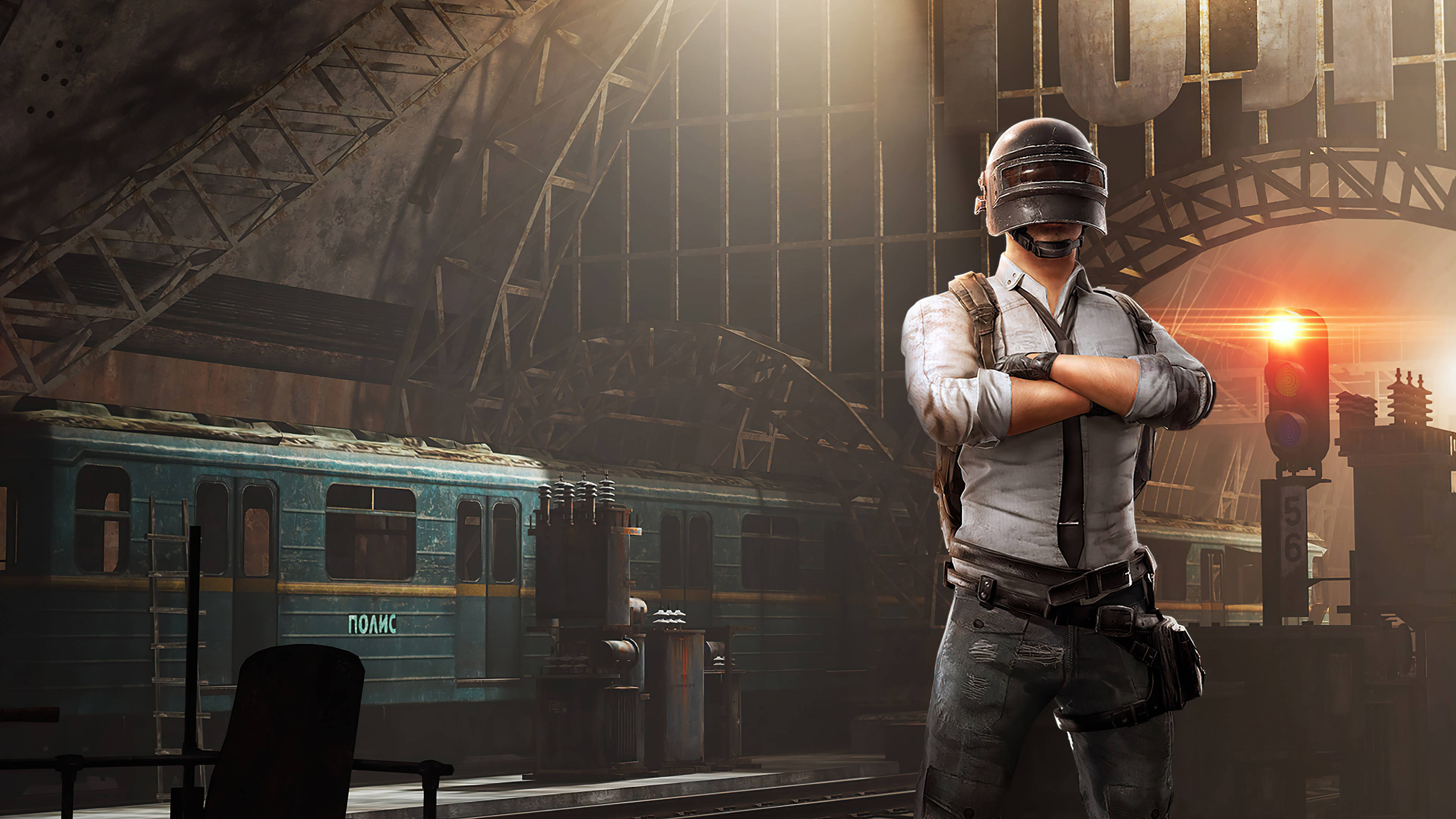 Pubg Lover 桌布 壁紙 — 一名身穿戰術裝備的士兵自信地交叉雙臂，站在陽光普照、廢棄的火車站內，旁邊有一節生鏽的藍色火車車廂。