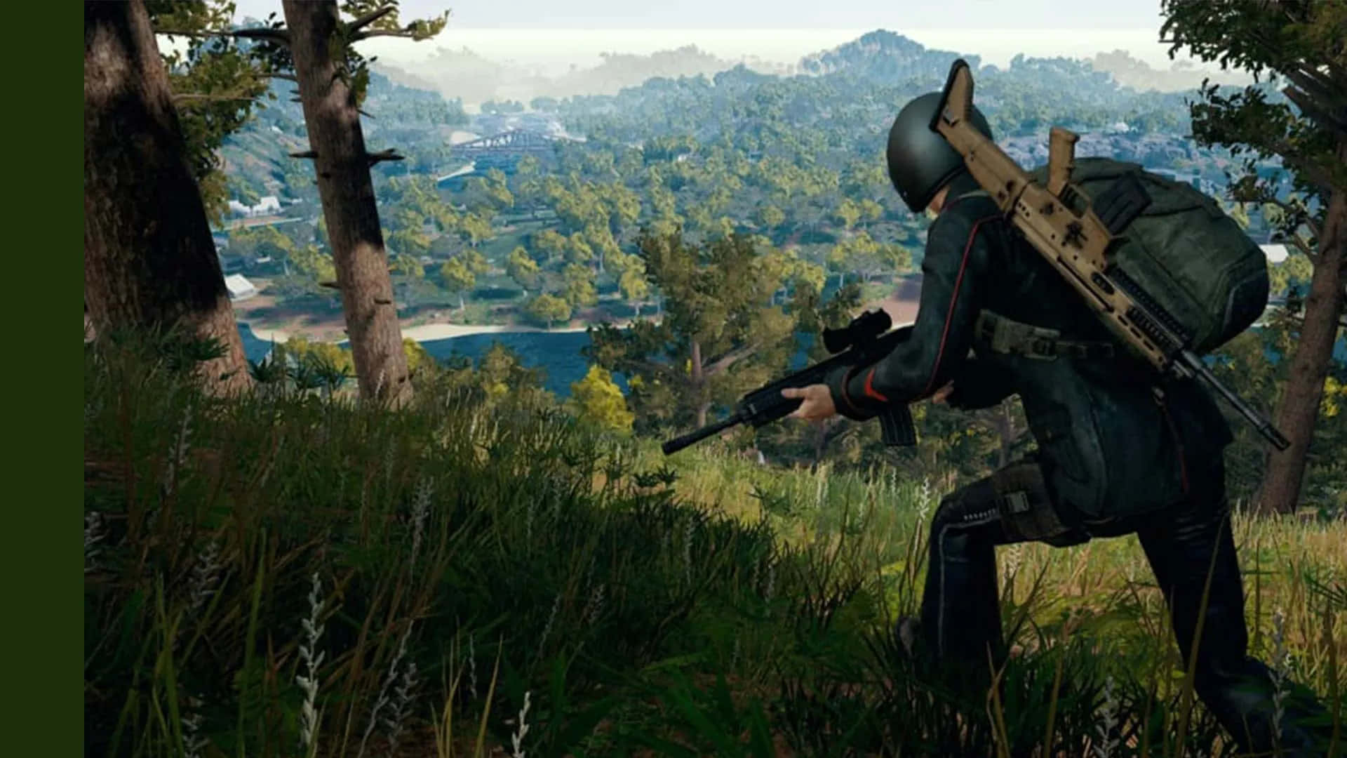 Pubg 1920x1080 桌布 壁紙 — 一名身穿戰術裝備的士兵蹲在高草叢中，俯瞰著一個林木茂密的山谷，遠處有建築物，在明亮的日光下。