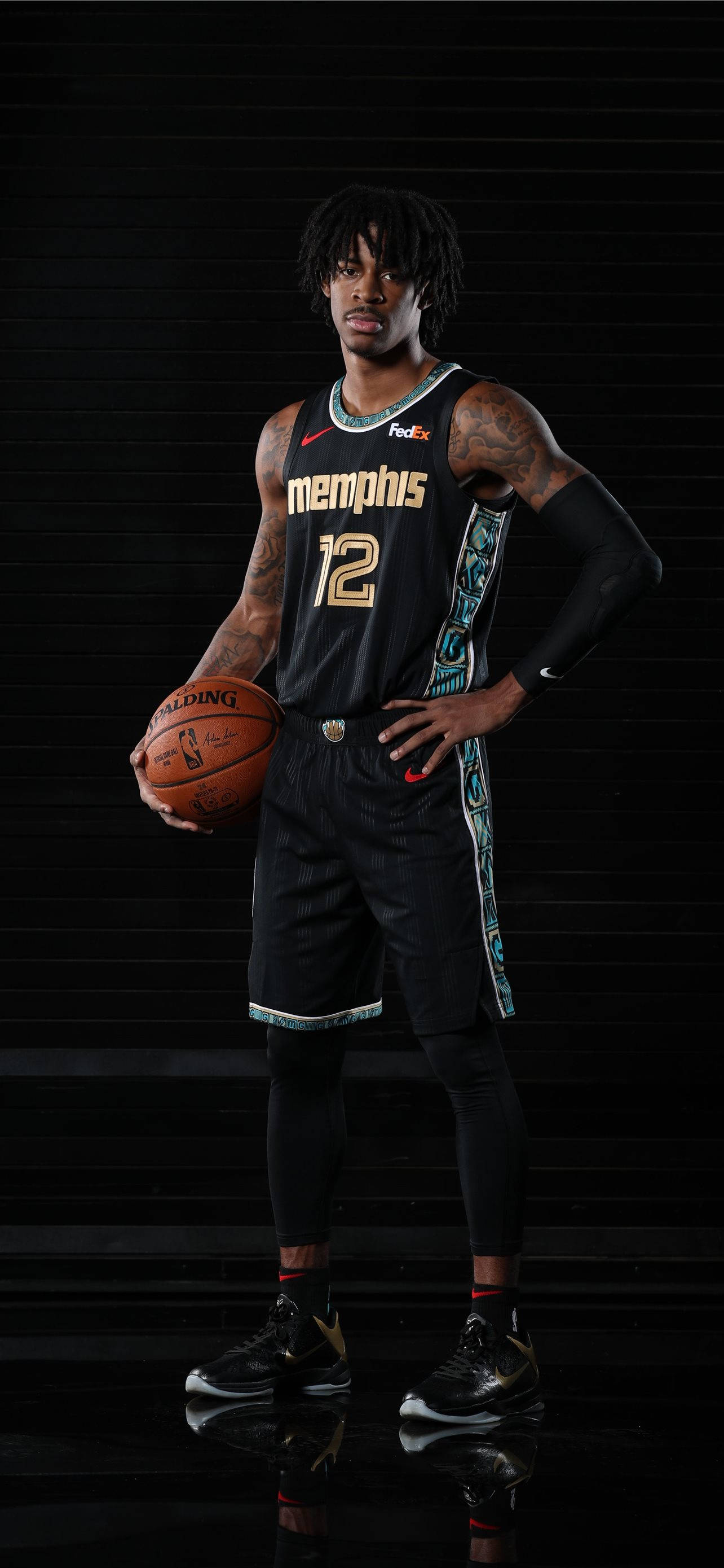 Grizzlies 桌布 壁紙 — 一名身穿曼菲斯灰熊隊球衣的籃球運動員自信地站在黑色攝影棚背景前，手持籃球，地板有反射效果。