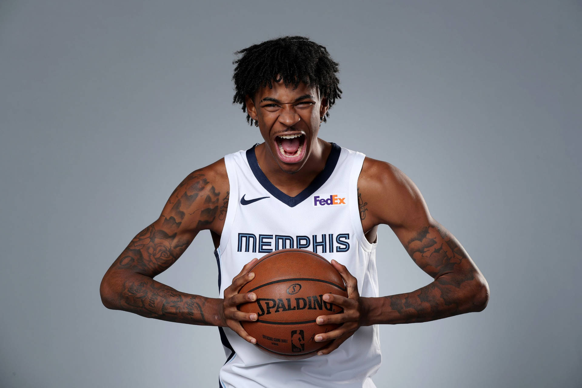 身穿曼菲斯球衣的籃球運動員拿著斯伯丁籃球大喊。 — Ja Morant 動圖 壁紙