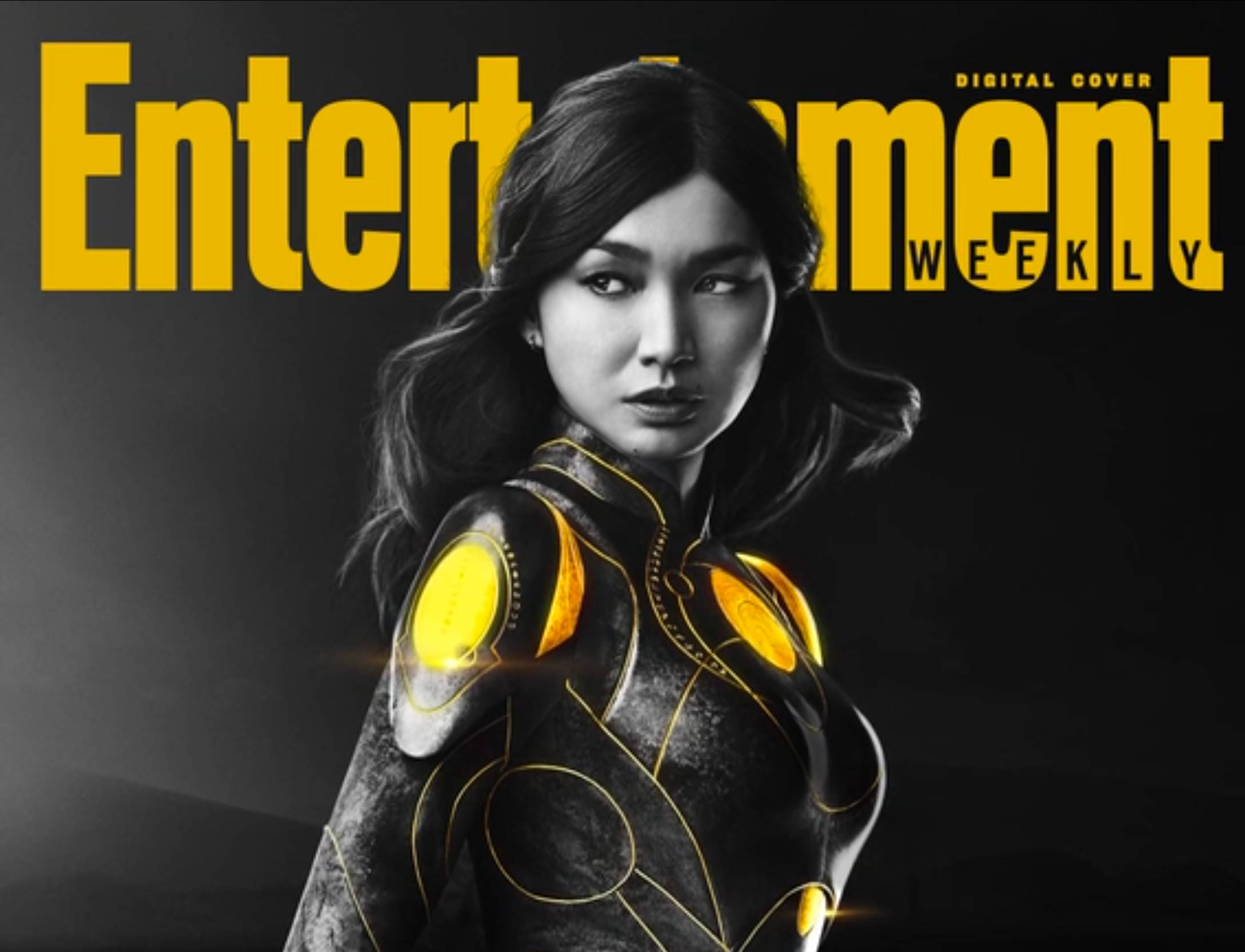Eternals 桌布 壁紙 — 一名身穿未來感黑色金色裝甲套裝的女性在深色背景前擺姿勢，帶有粗體黃色「Entertainment Weekly」文字。