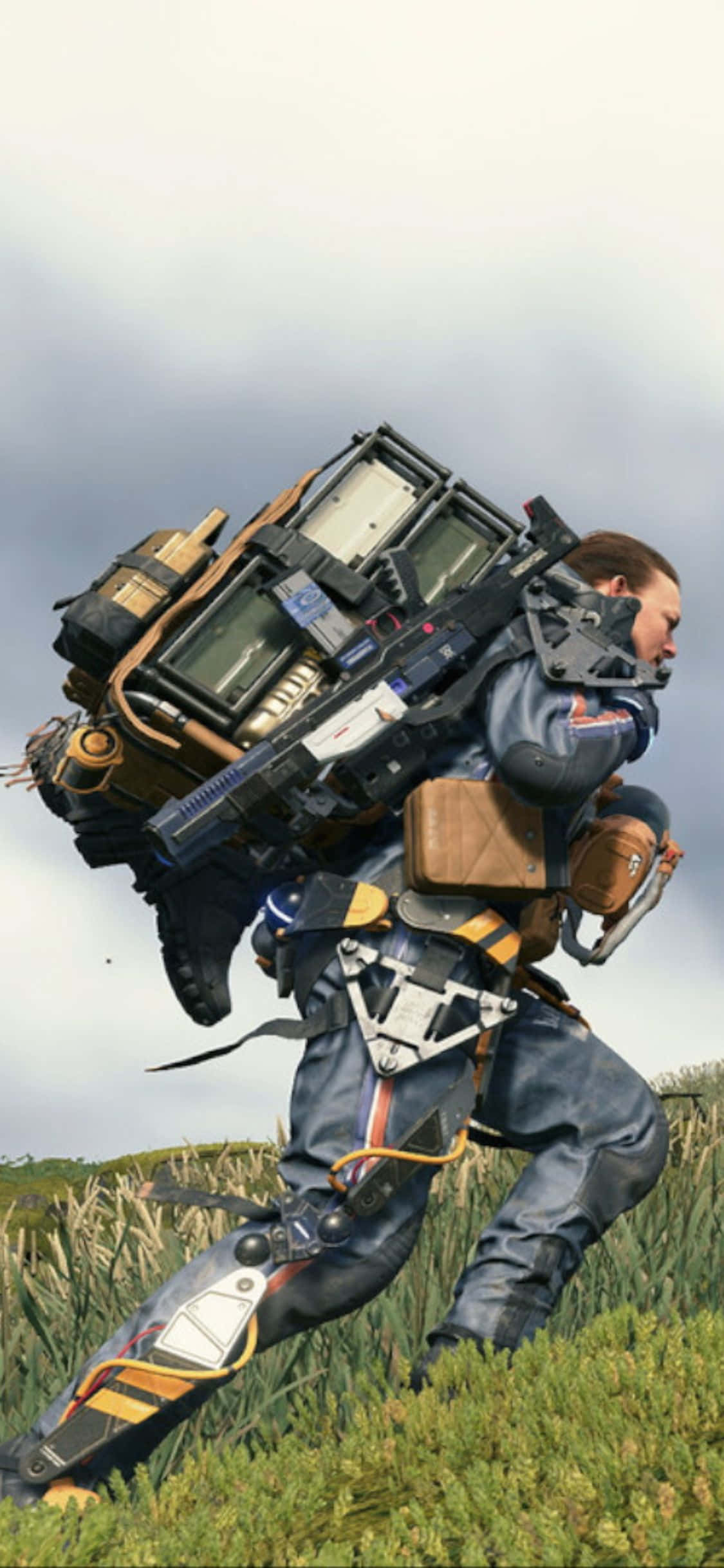 iPhone Xs Death Stranding 桌布 壁紙 — 一名身穿未來裝備的士兵在陰天背著巨大的機械背包穿過高草奔跑。