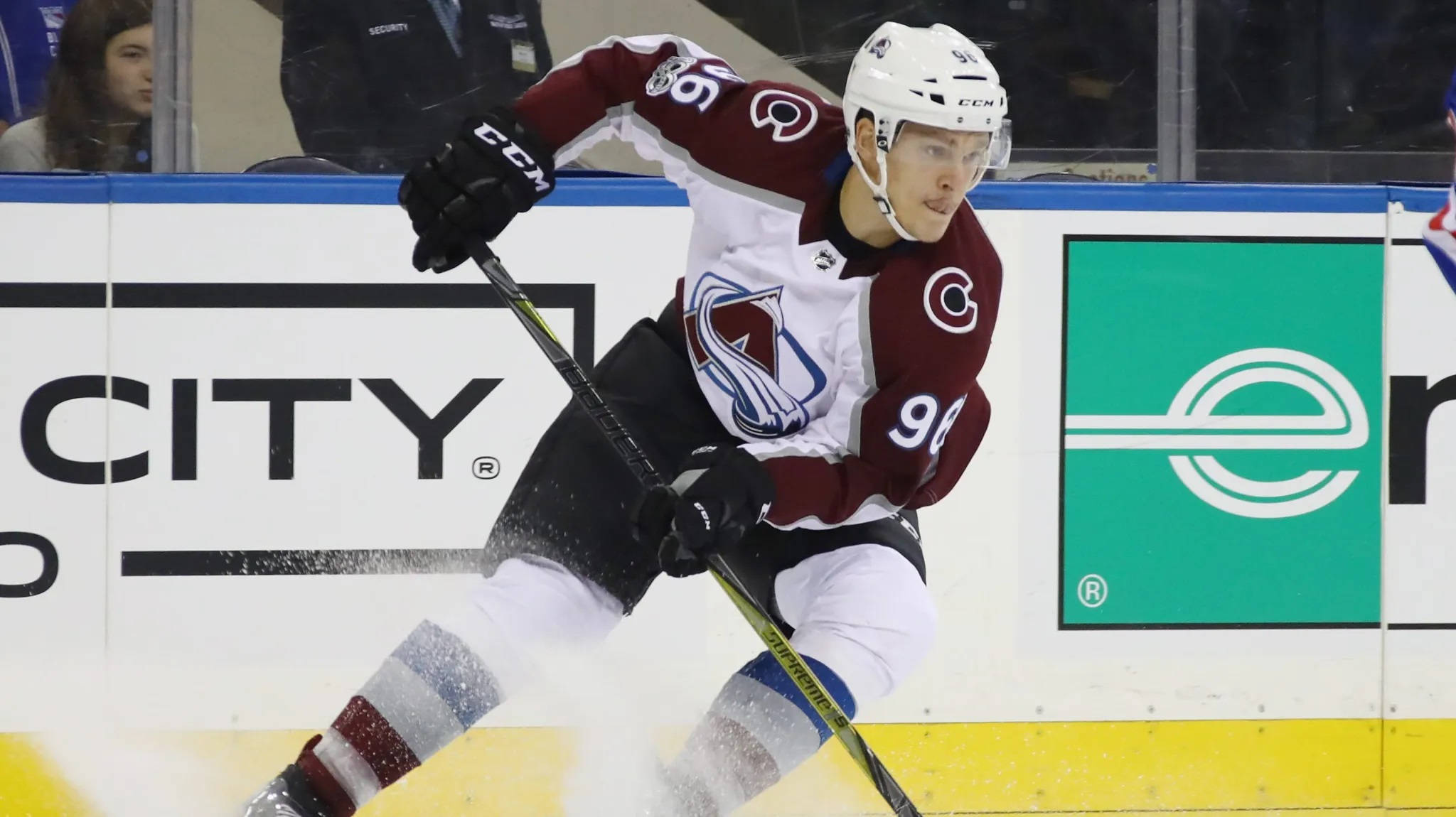 hockey 桌布 壁紙 — 一名身穿栗色和白色球衣的冰上曲棍球運動員在比賽中於冰上激烈滑行，球桿中帶有冰球。