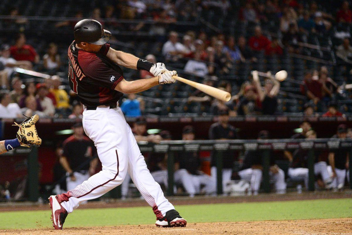 Paul Goldschmidt 桌布 壁紙 — 一名身穿栗色和白色球衣的棒球選手在夜間比賽中揮棒擊球，看台上坐滿了觀眾。
