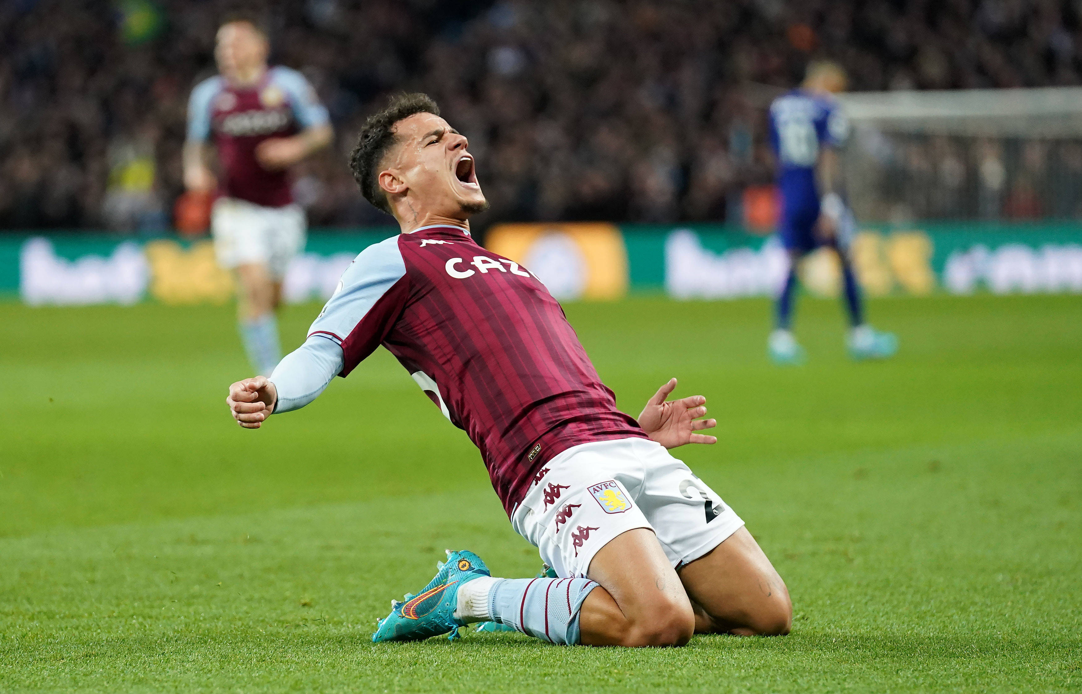 Coutinho 桌布 壁紙 — 一名身穿栗色球衣的足球運動員在夜間比賽中跪在草地上，張開嘴巴狂喜地慶祝。