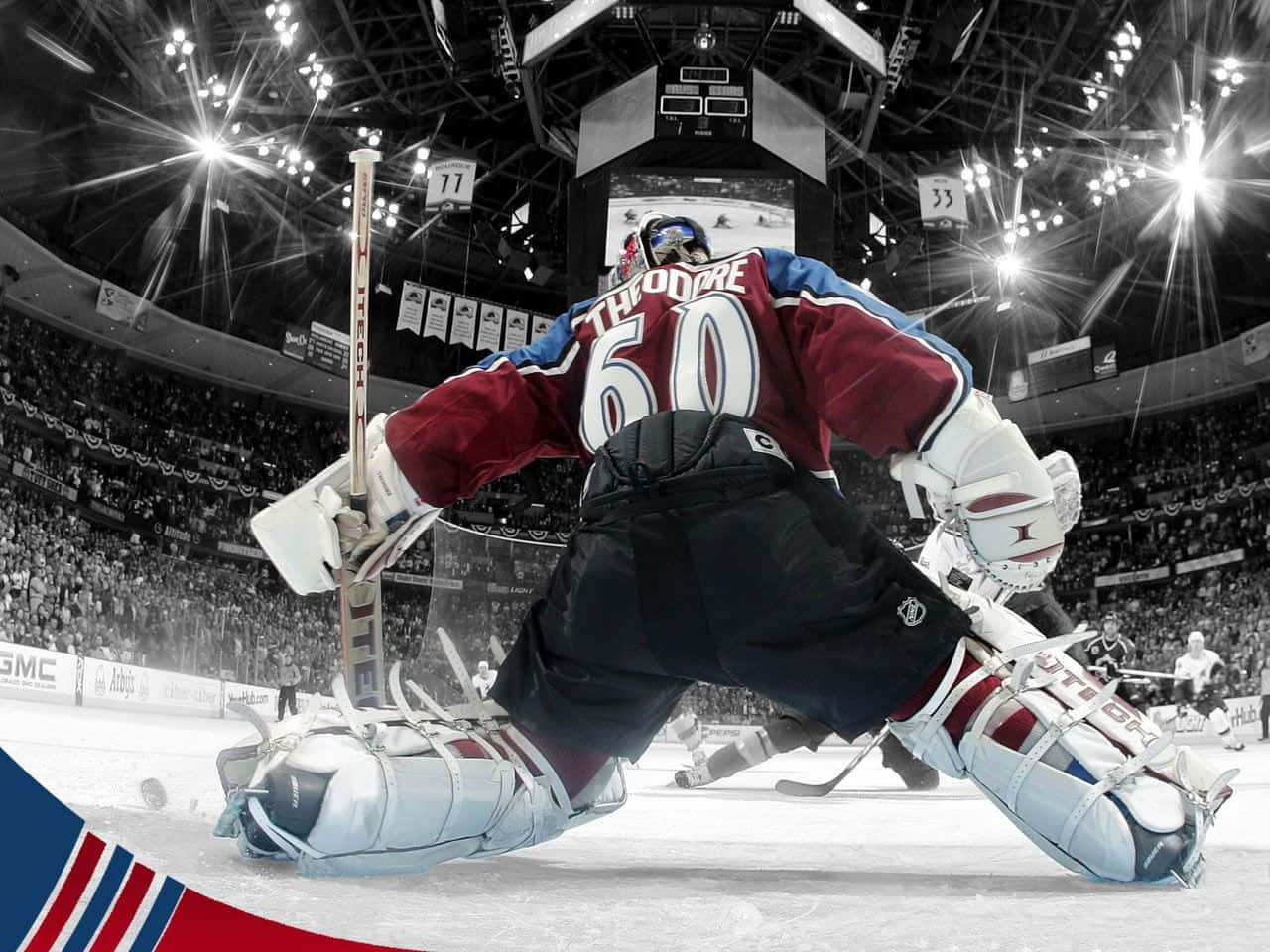 hockey 桌布 壁紙 — 一名身穿栗藍色球衣的冰球守門員在明亮的場館燈光下，在觀眾席球迷的注視中低身撲救阻擋射門。