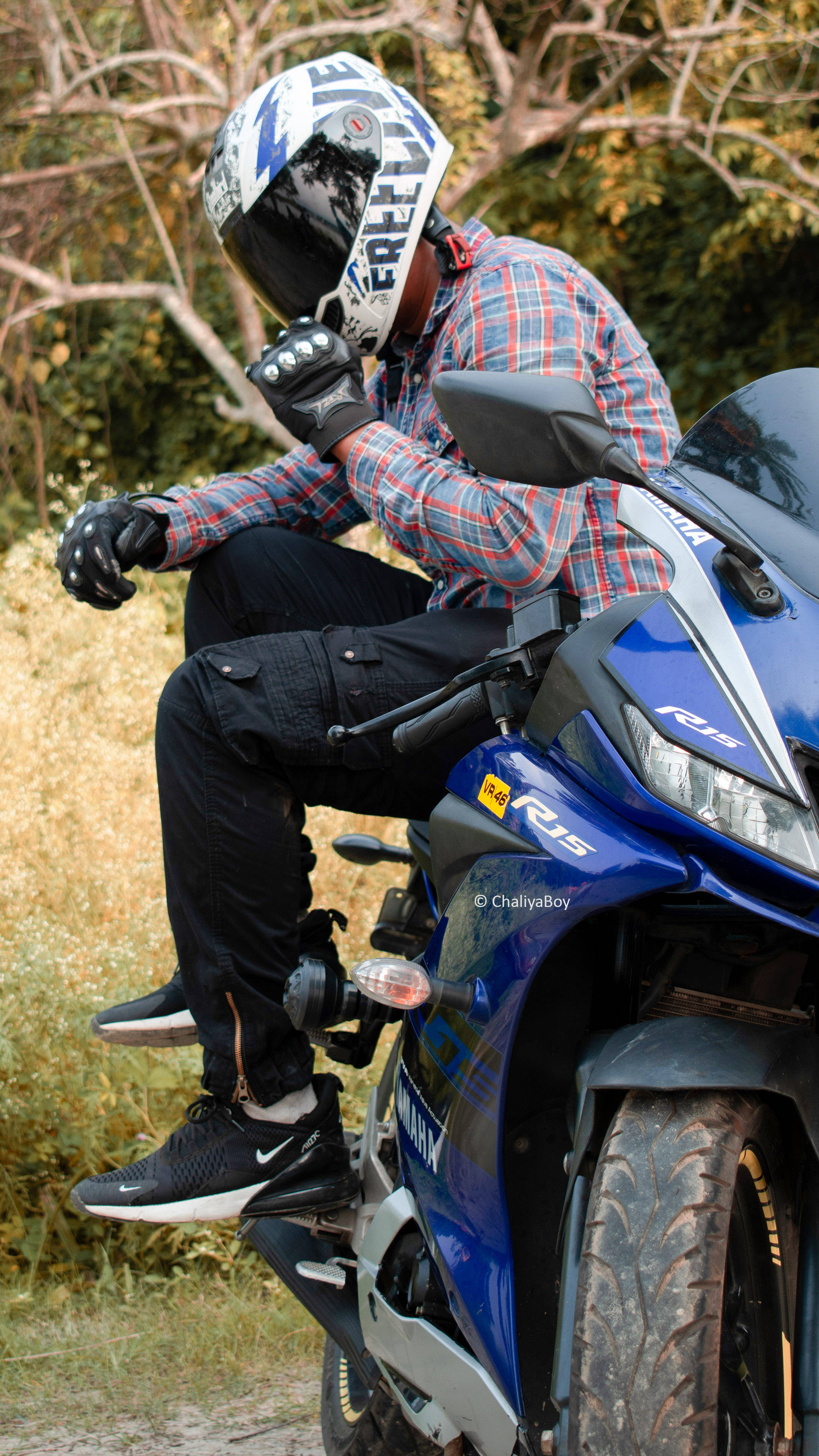 機車 桌布 壁紙 — 一名身穿格紋襯衫和頭盔的摩托車手，坐在藍色Yamaha R15機車上，周圍是乾草和樹木。