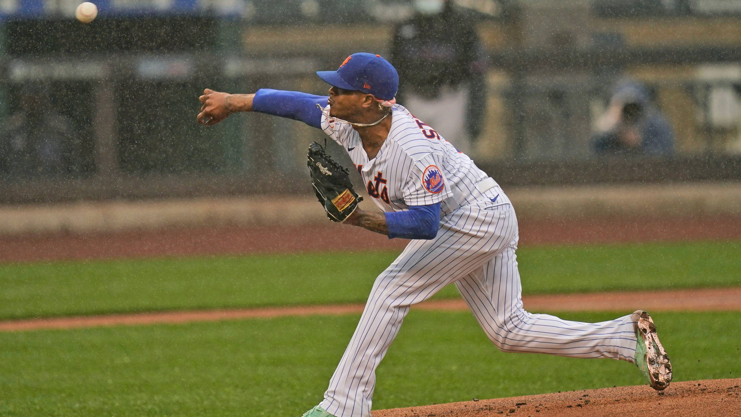 Marcus Stroman 桌布 壁紙 — 一名身穿條紋球衣的棒球運動員在雨中比賽時在綠色場地上投球。
