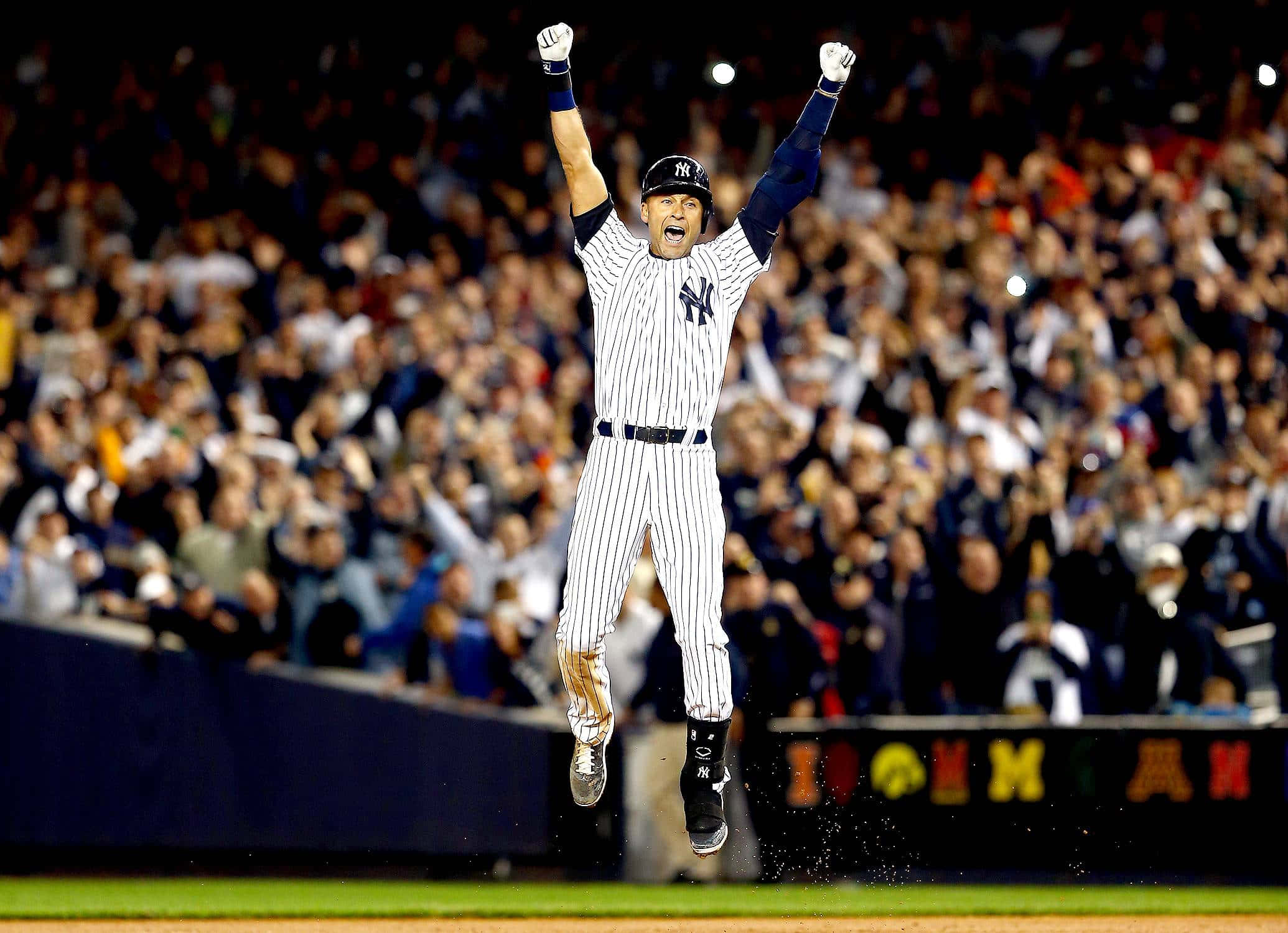 Derek Jeter 桌布 壁紙 — 一名身穿條紋球衣的棒球選手在球場燈光下高舉雙臂，勝利地跳躍。