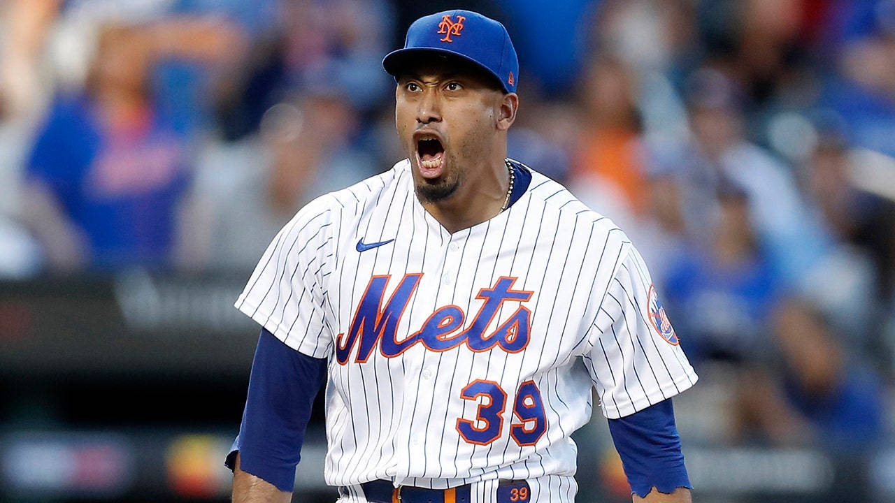 New York Mets 桌布 壁紙 — 一名身穿條紋球衣的紐約大都會棒球運動員在比賽中激情吶喊，身後是模糊的球場人群。