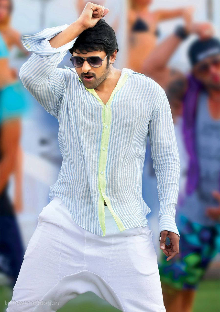 Prabhas Mirchi 桌布 壁紙 — 一名身穿條紋襯衫和白色褲子的男子，戴著太陽眼鏡，擺出一個拳頭高舉的動態姿勢。
