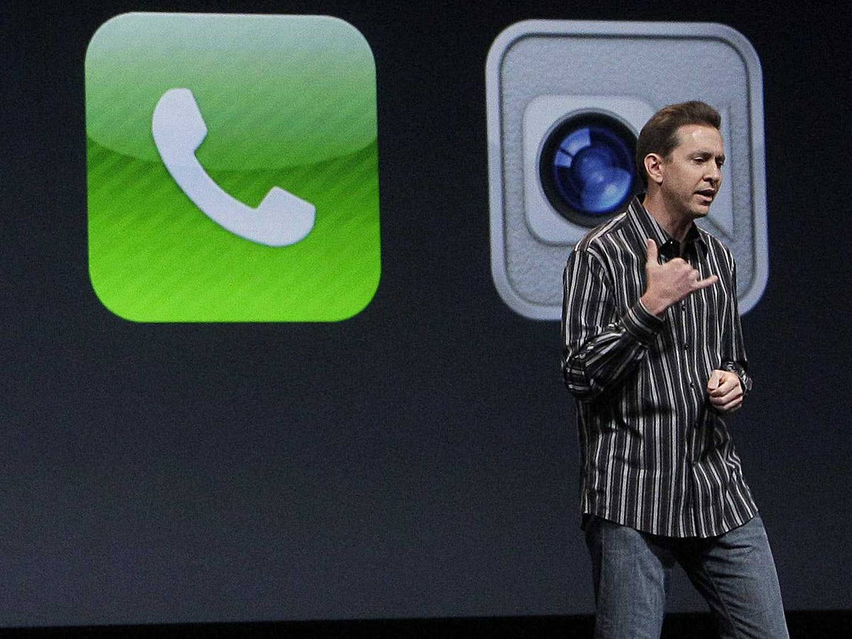 Software 桌布 壁紙 — 一名身穿條紋襯衫的男子在舞台上，旁邊有巨大的iPhone應用程式圖示，分別代表電話和相機，他正在做手勢。