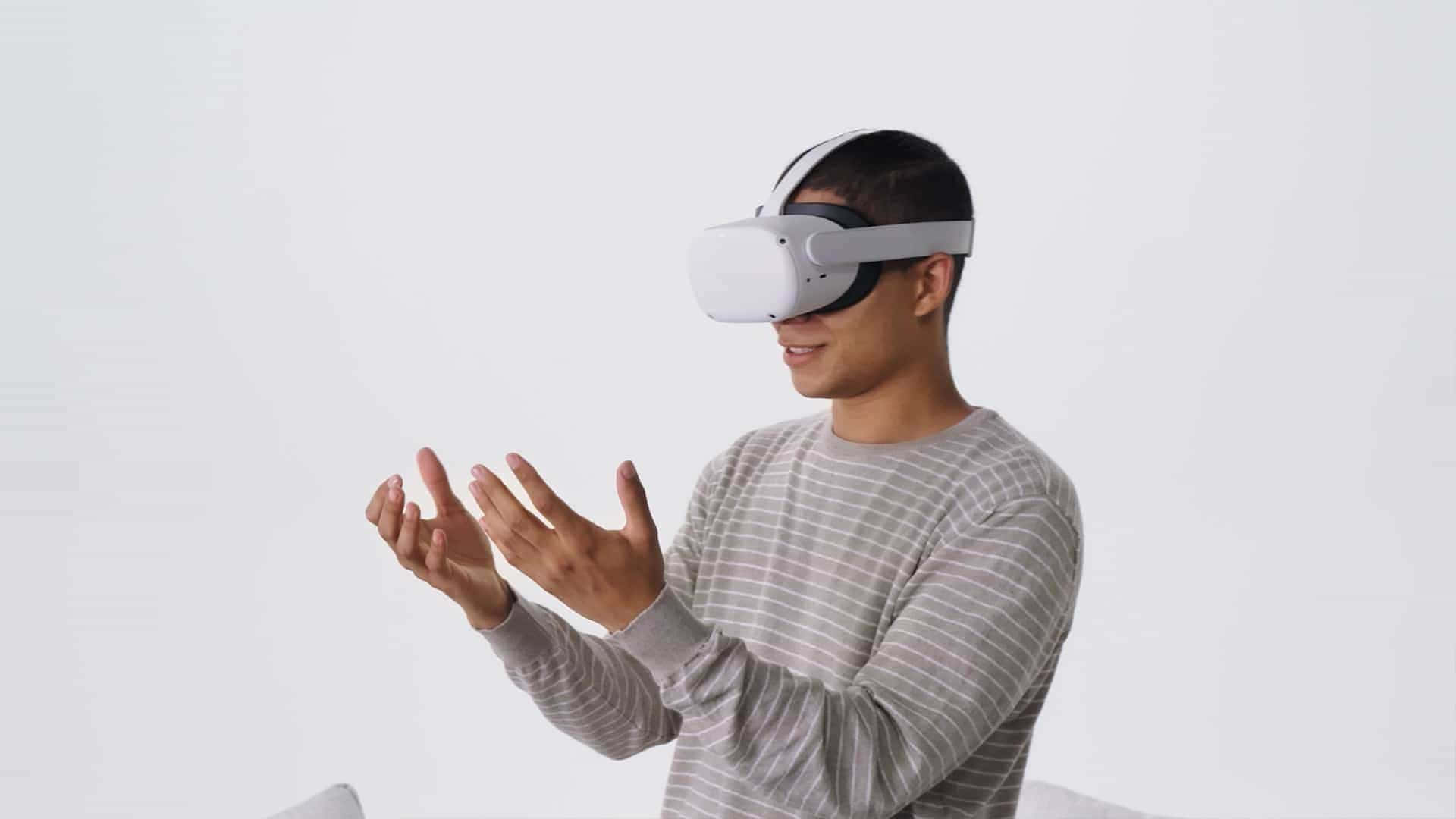 Oculus Quest 2 桌布 壁紙 — 一名身穿條紋襯衫的男子戴著白色VR頭戴式裝置，在純白色背景前用雙手做手勢。