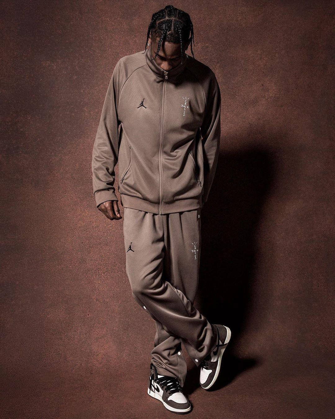 崔維斯·史考特 桌布 壁紙 — 一名身穿棕色Jordan運動服的男士站在有紋理的棕色背景前，戲劇性的燈光投射出強烈的陰影。
