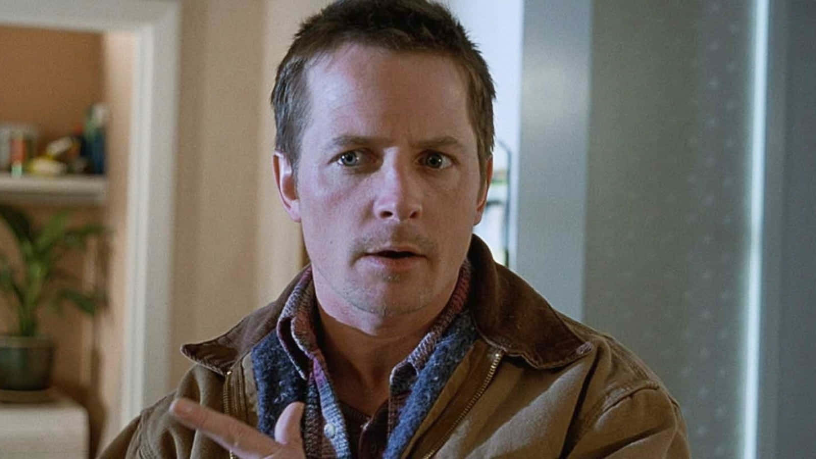 michael j fox 桌布 壁紙 — 一名身穿棕色外套的男子在室內做出手勢，表情驚訝。