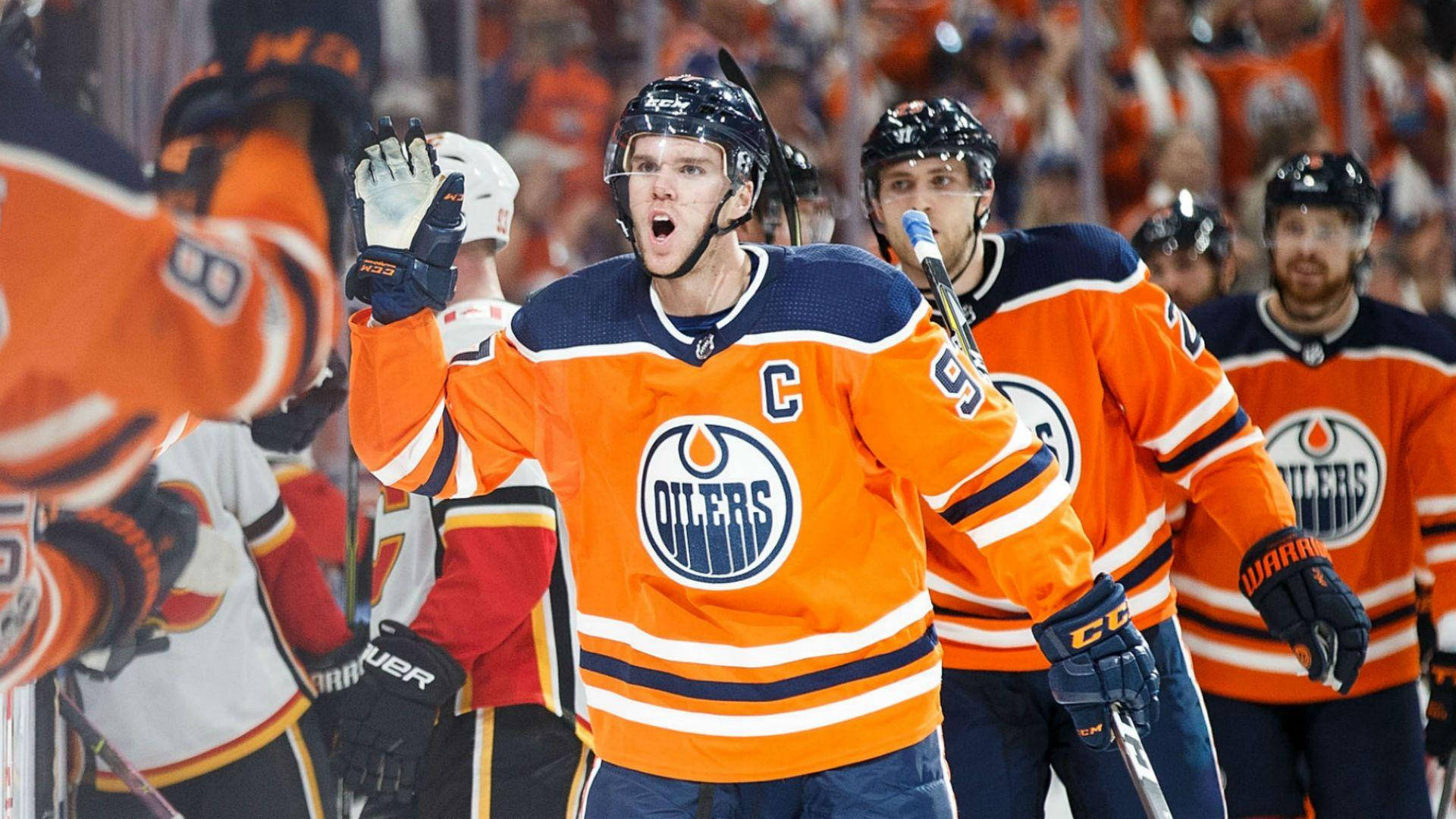 hockey 桌布 壁紙 — 一名身穿橙色Oilers球衣、帶有隊長'C'標誌的冰球運動員在比賽中於冰上熱情慶祝。