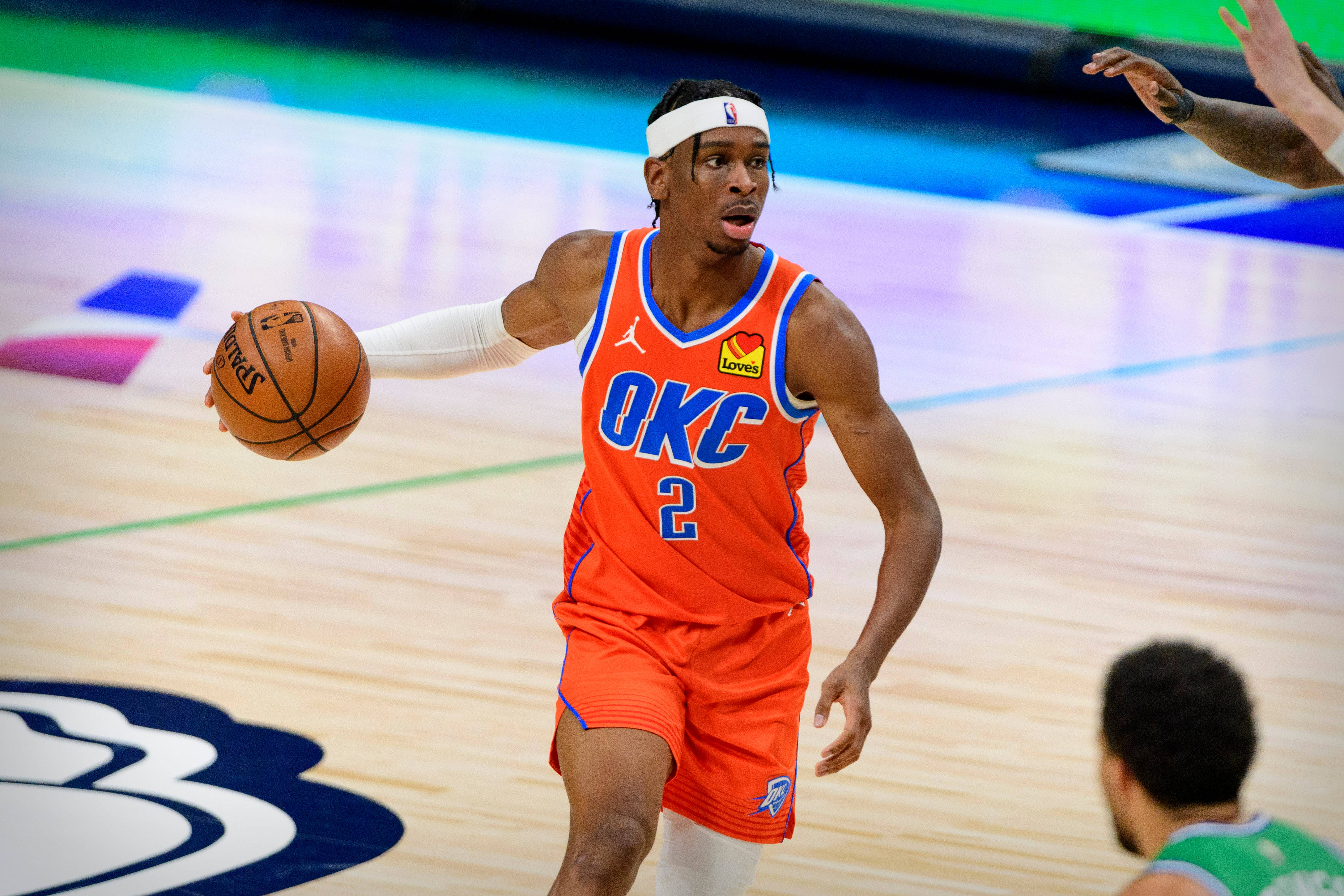籃球 桌布 壁紙 — 一名身穿橙色OKC球衣的籃球運動員在拋光木地板上比賽時專注地運球。