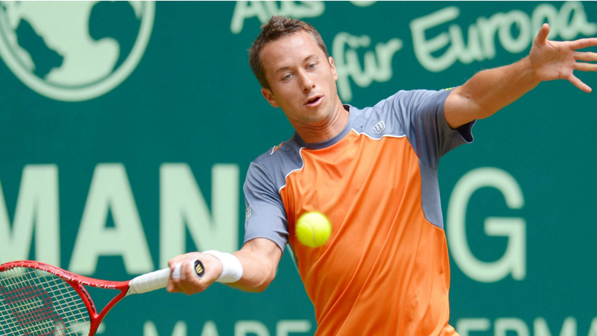 Tennis 桌布 壁紙 — 一名身穿橙色和灰色襯衫的男性網球選手，揮動紅色球拍擊打黃色球，背景是帶有白色文字的綠色牆壁。