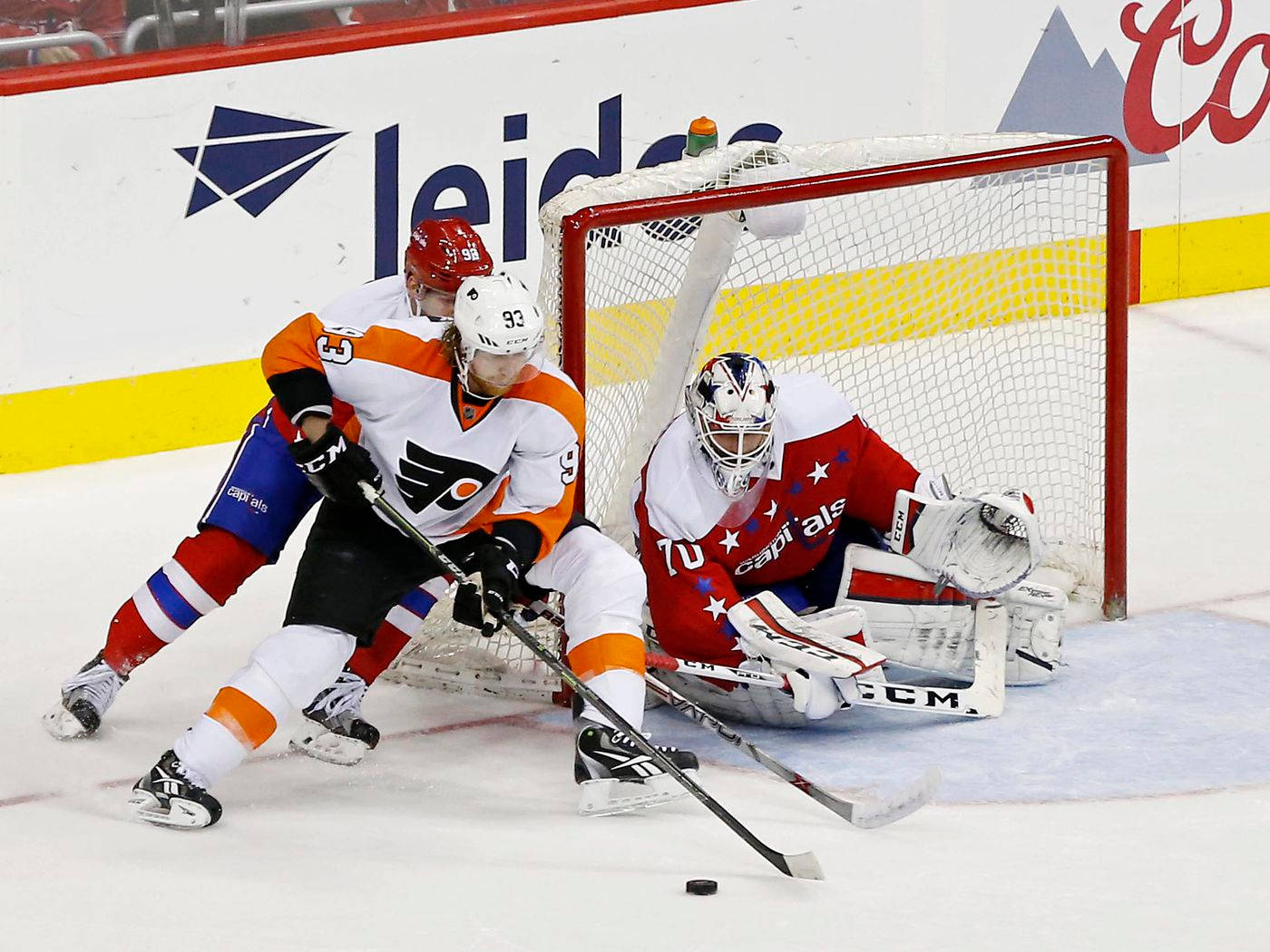 hockey 桌布 壁紙 — 一名身穿橙色和白色球衣的冰球運動員在球門附近爭奪冰球，而身穿紅色和白色裝備的守門員飛身撲救。