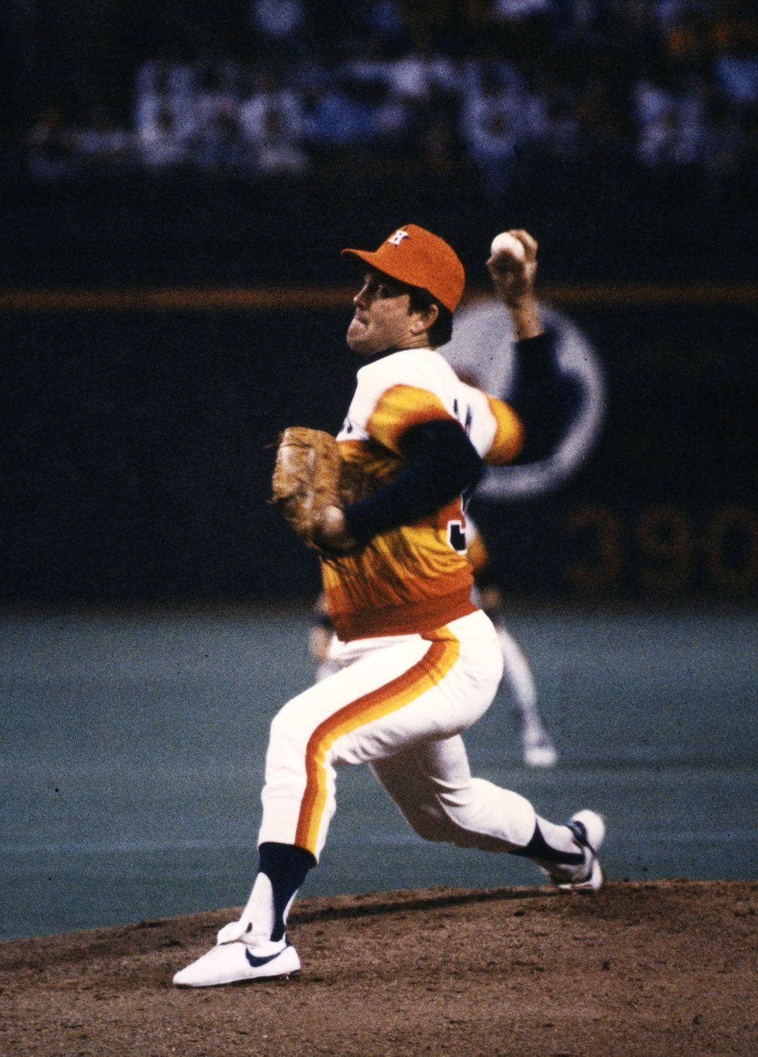 Nolan Ryan 桌布 壁紙 — 一名身穿橙色和白色球衣的棒球投手在夜間比賽中於球場燈光下投球。