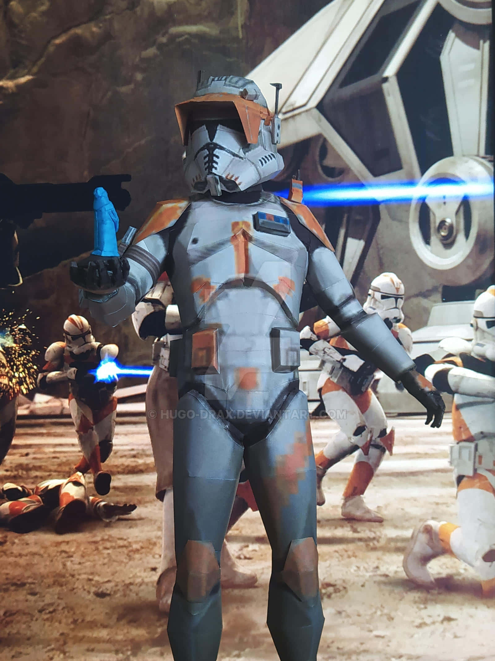 The Order 66 桌布 壁紙 — 一名身穿橙色和白色盔甲的複製人突擊兵，手持藍色光劍，在沙漠戰場上與其他突擊兵和星艦一起準備就緒。