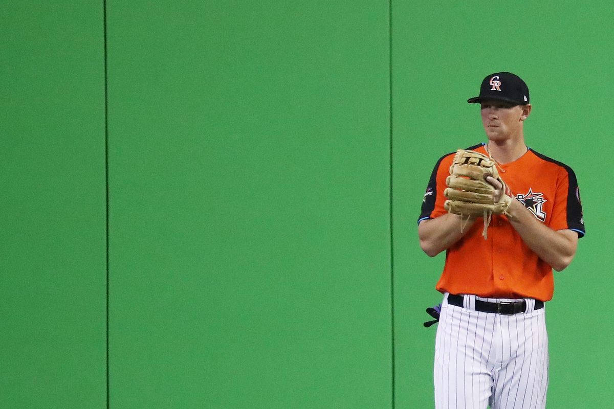 Dj Lemahieu 桌布 壁紙 — 一名身穿橙色和黑色球衣的棒球運動員，站在純綠色牆壁前，手持手套。