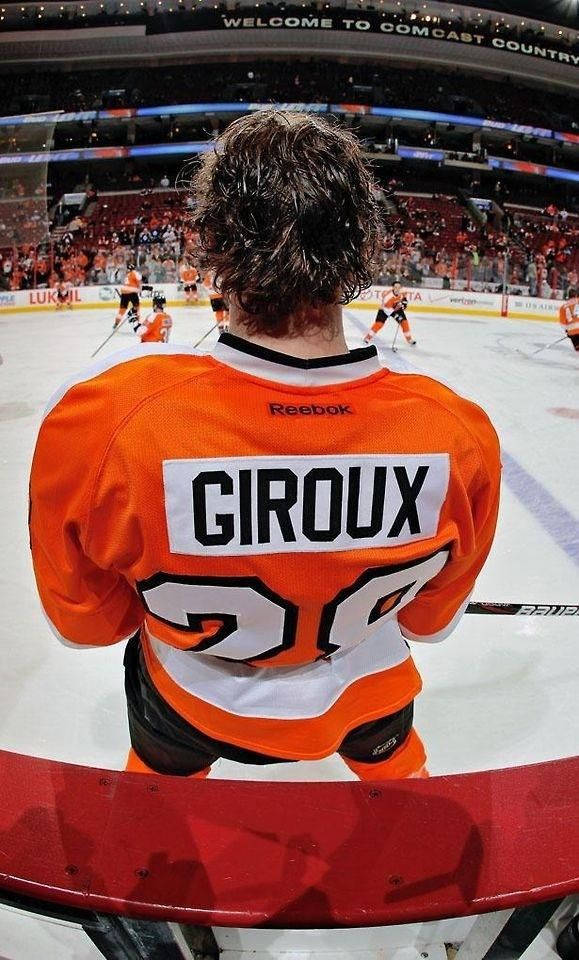 運動 桌布 壁紙 — 一名身穿橙色球衣、印有「Giroux 20」的冰球運動員在比賽期間站在後備席上俯瞰冰場。
